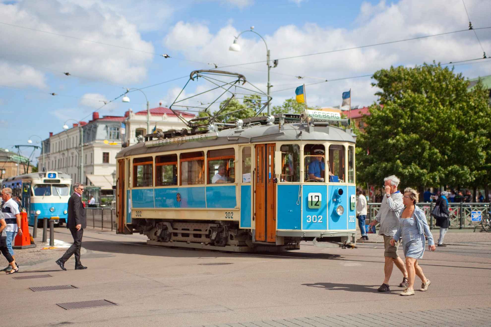 Op straat in het centrum van Göteborg rijdt een ouderwetse tram. Het is zomer en daglicht.