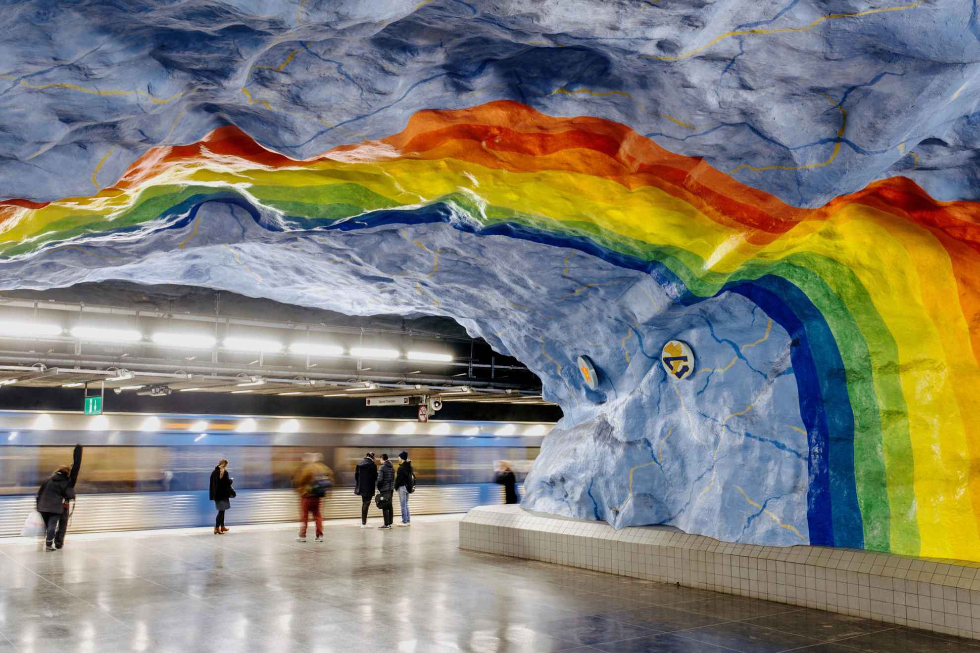 Een regenboog in levendige kleuren geschilderd op het plafond in een metrostation.