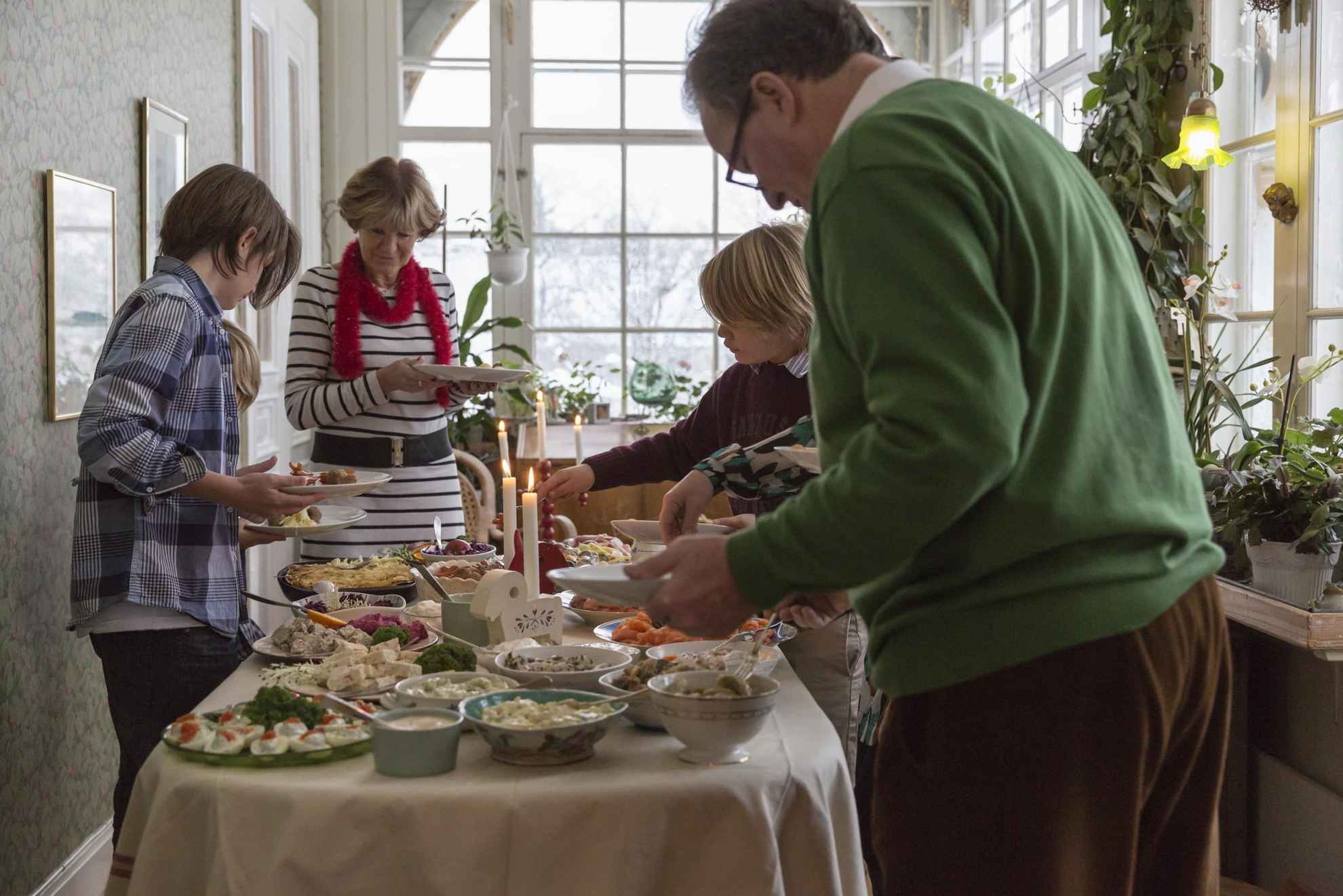 Familieleden staan rond een tafel en bedienen zich aan het kerstbuffet.
