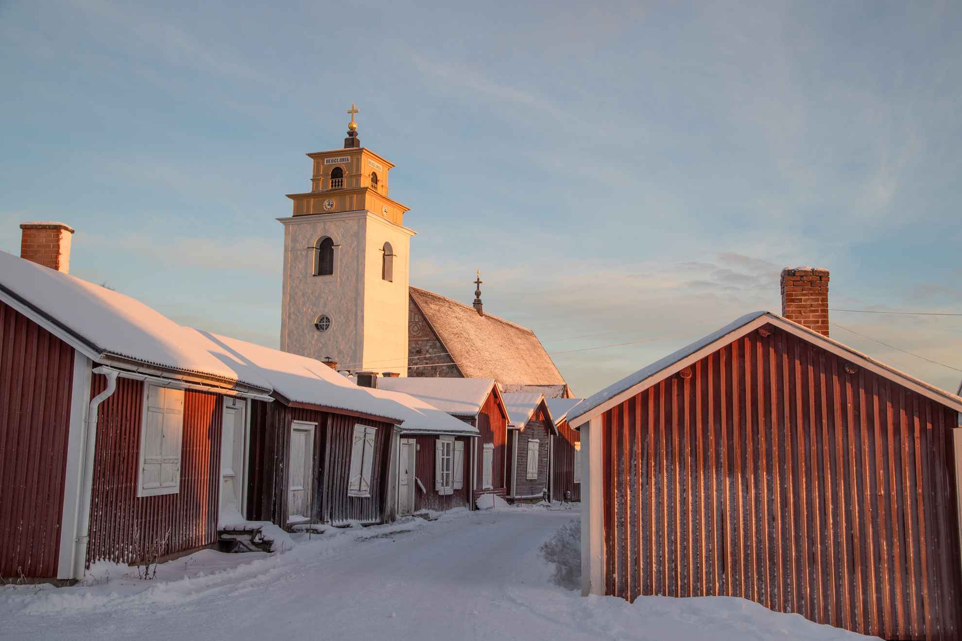Rode huisjes en de witte kerktoren in de kerkstad Gammelstad tijdens de winter.