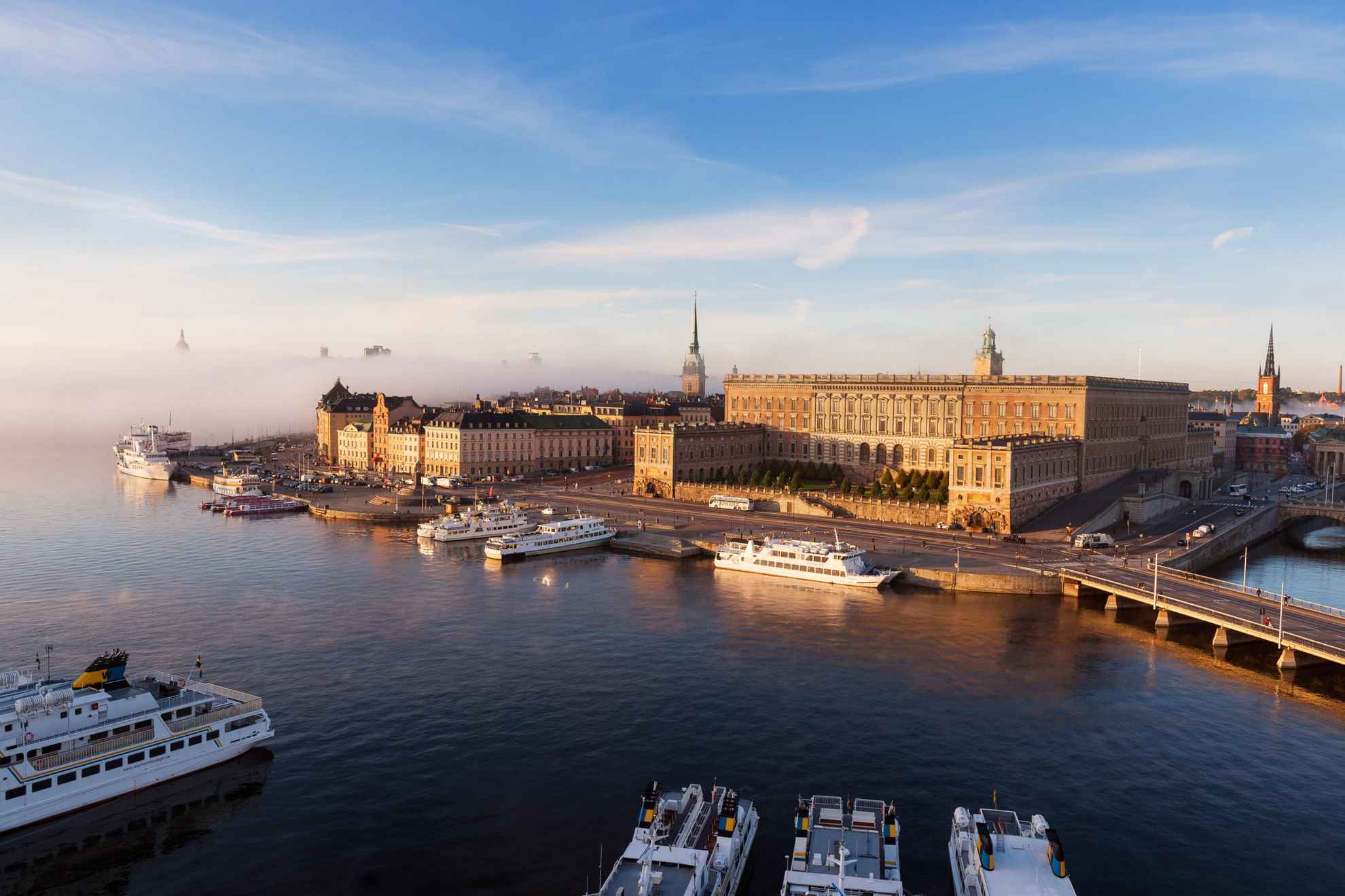 Luchtfoto uitzicht over het Koninklijk Paleis en andere gebouwen in de stad Stockholm. Boten liggen afgemeerd langs de haven.