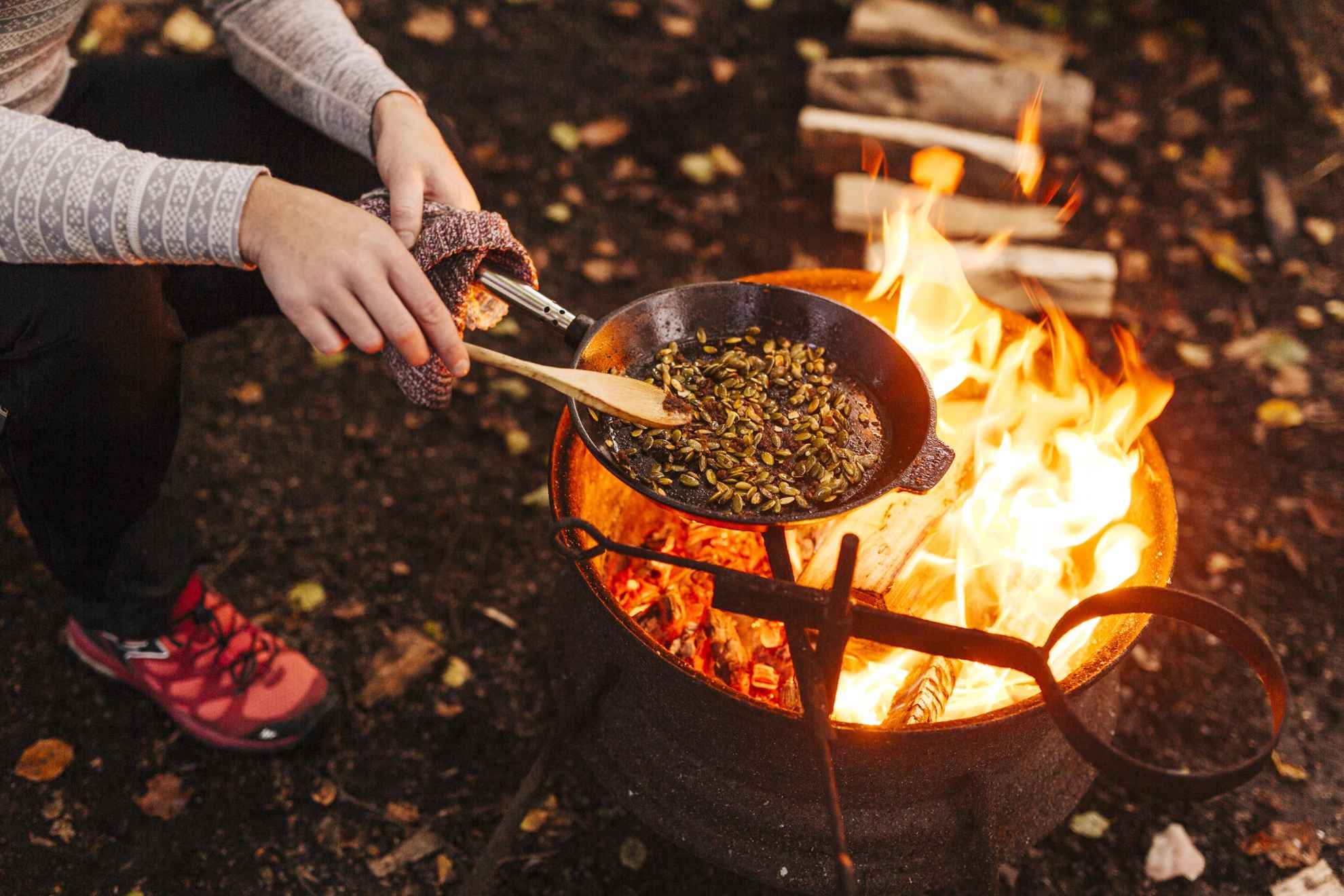 Iemand bakt eten boven een open vuur in het bos.