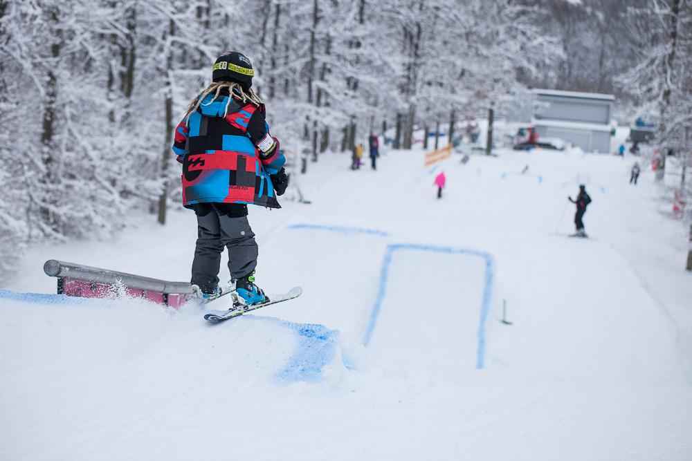 Een kind dat met kleine sprongen van een skihelling skiet.