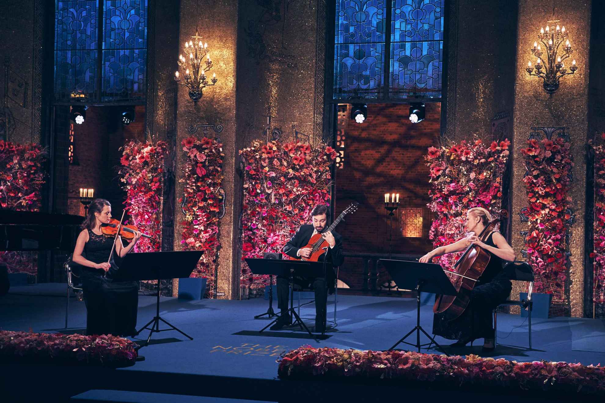 Een gitarist, een cellist en een violist treden op tijdens de Nobelprijsuitreiking.