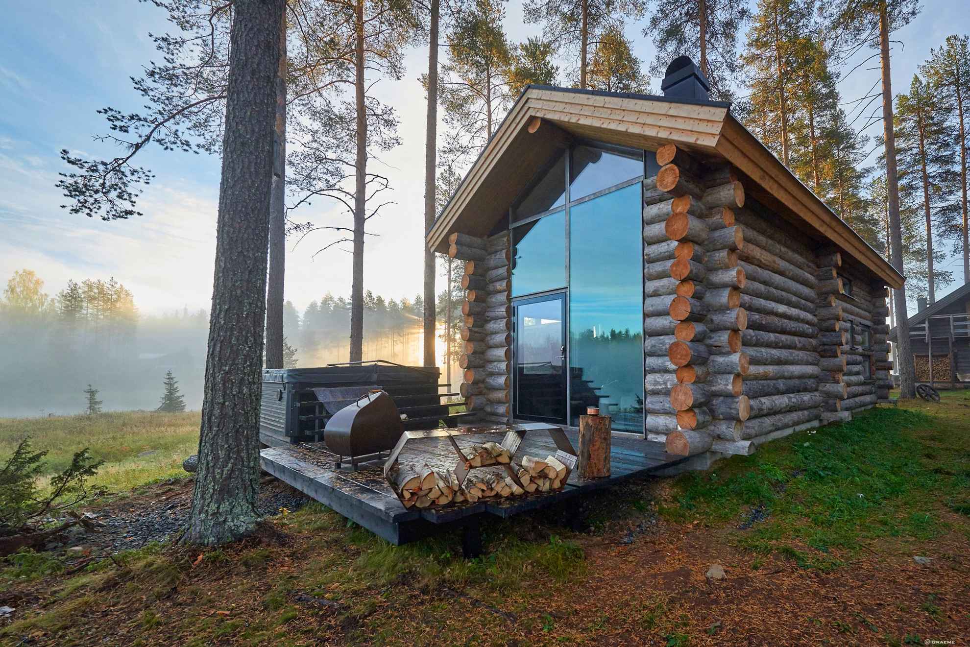 Een houten huis met grote ramen en een houten terras in de herfst.