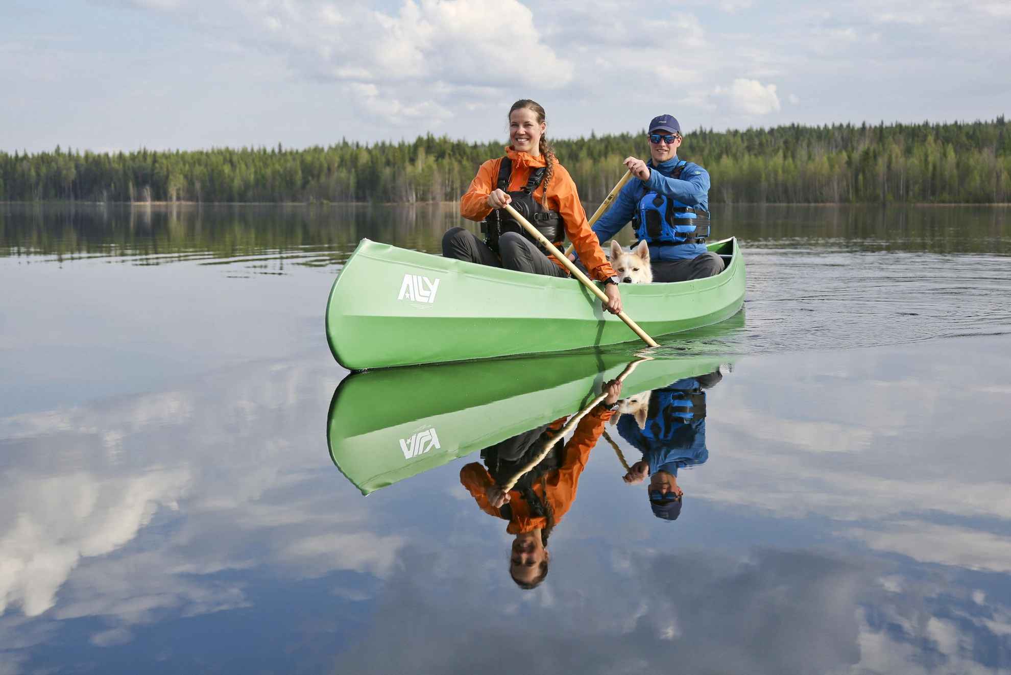 Een man en een vrouw die samen kanoën in water omringd door bos.