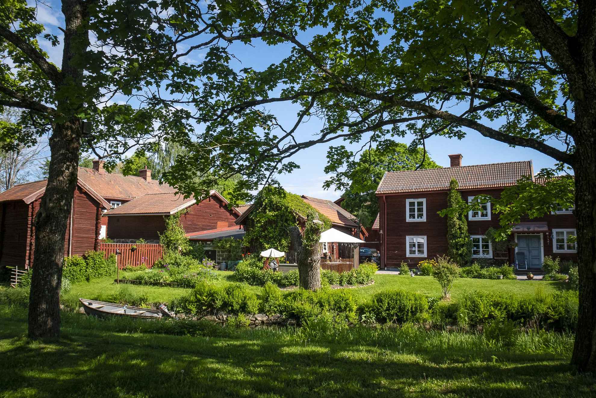 Verschillende traditionele huizen beschilderd met de beroemde verf Falu Rödfärg omgeven door groen.