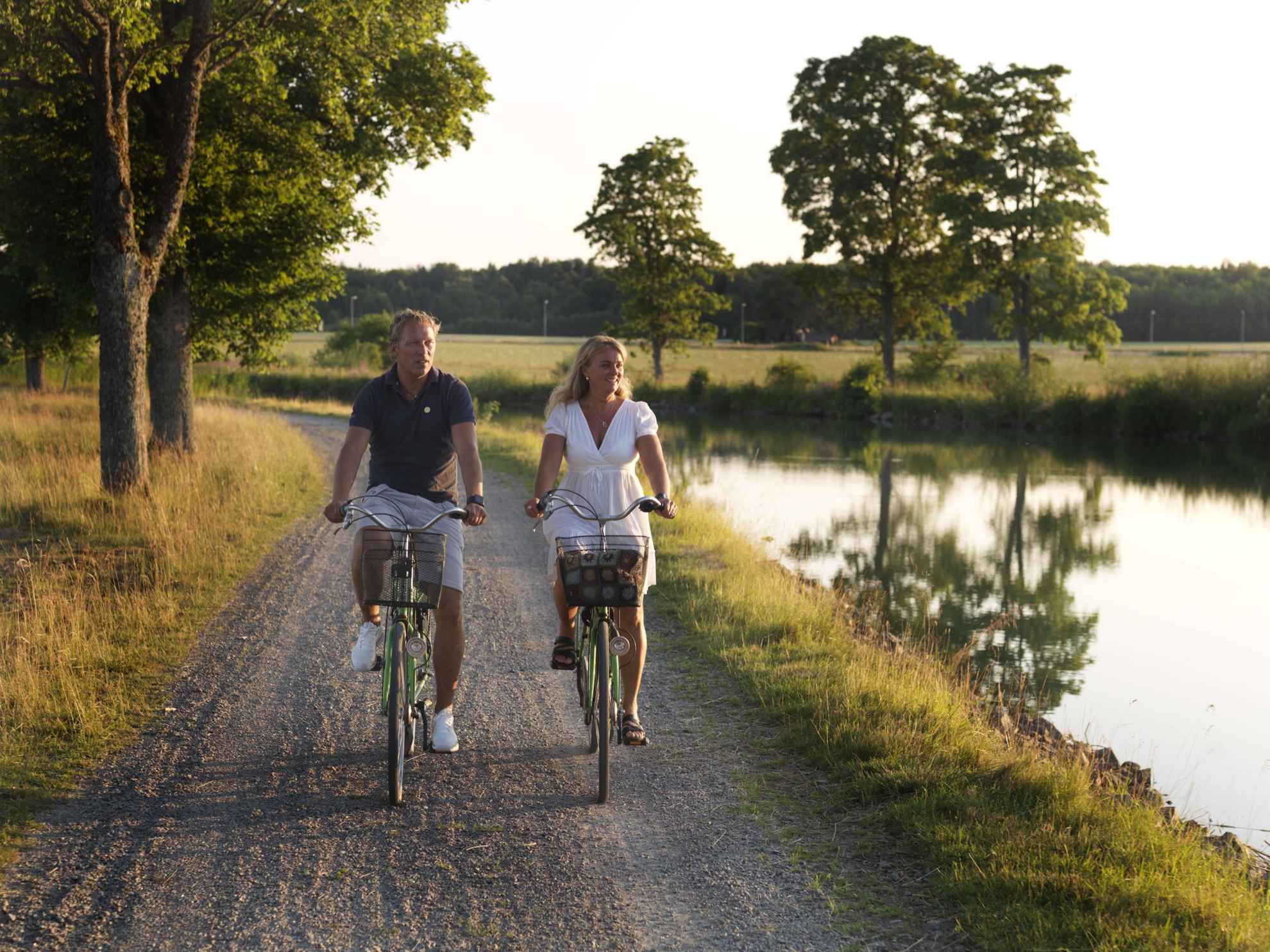 Een man en een vrouw fietsen in de zomer langs het Götakanaal.