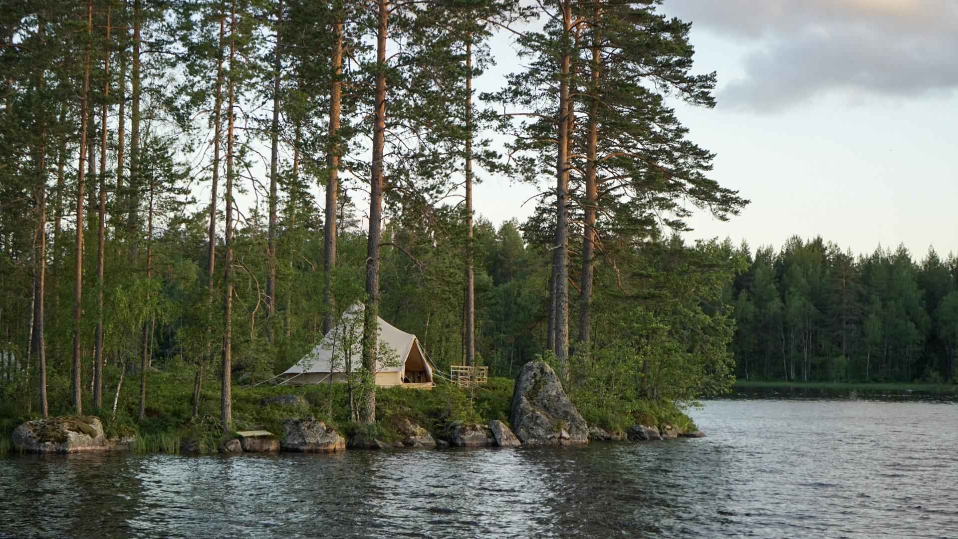 Een luxe canvas tent aan een meer in het bos in Värmland.