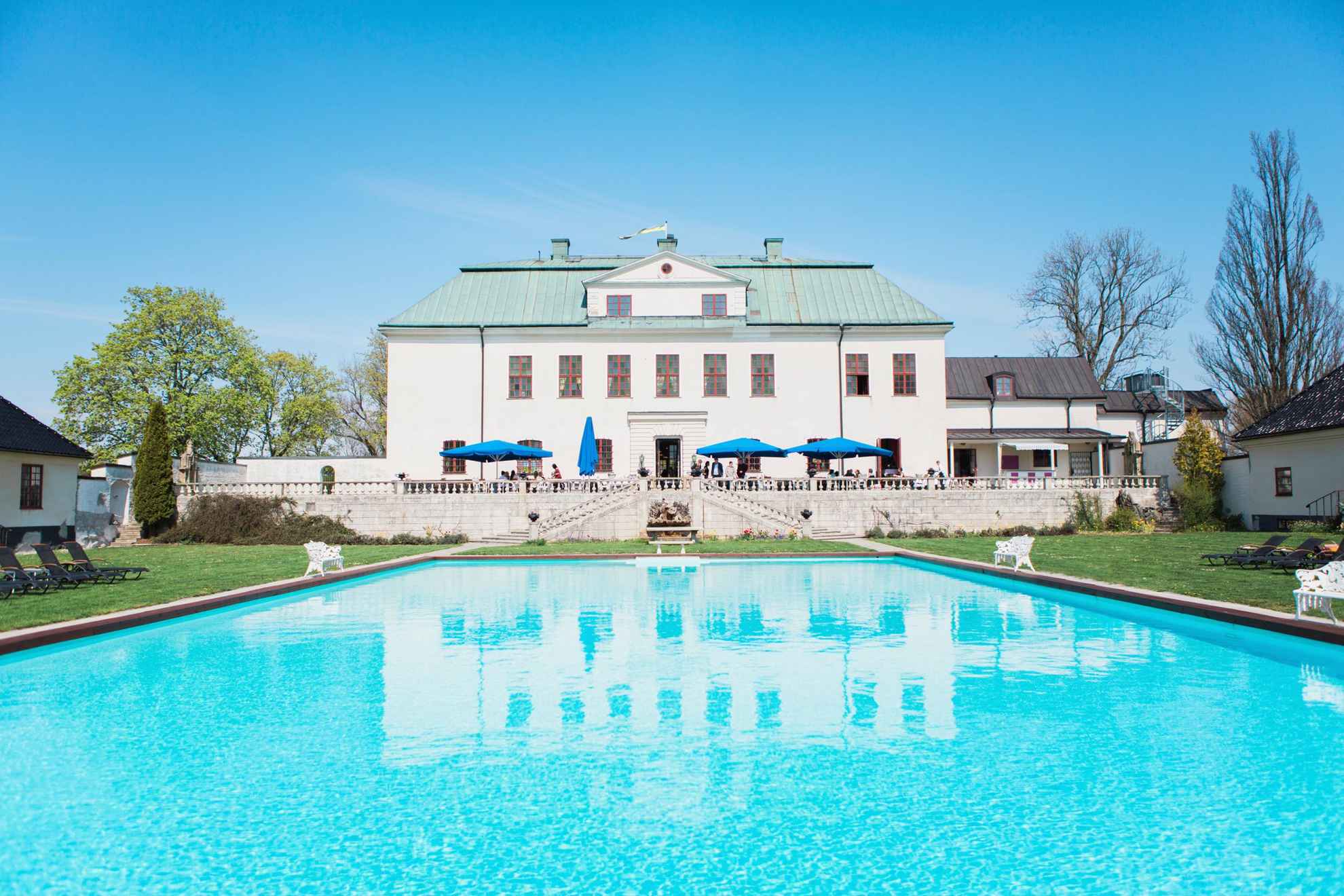 De achtertuin van kasteel Häringe, met een zwembad en een groot terras.