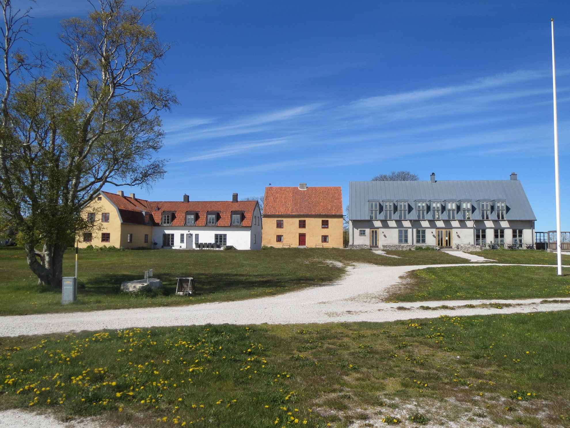 Een hotel op het platteland bij Fårö Gotland. Twee oude en een modern gebouw gezien vanaf een kleine landweg.