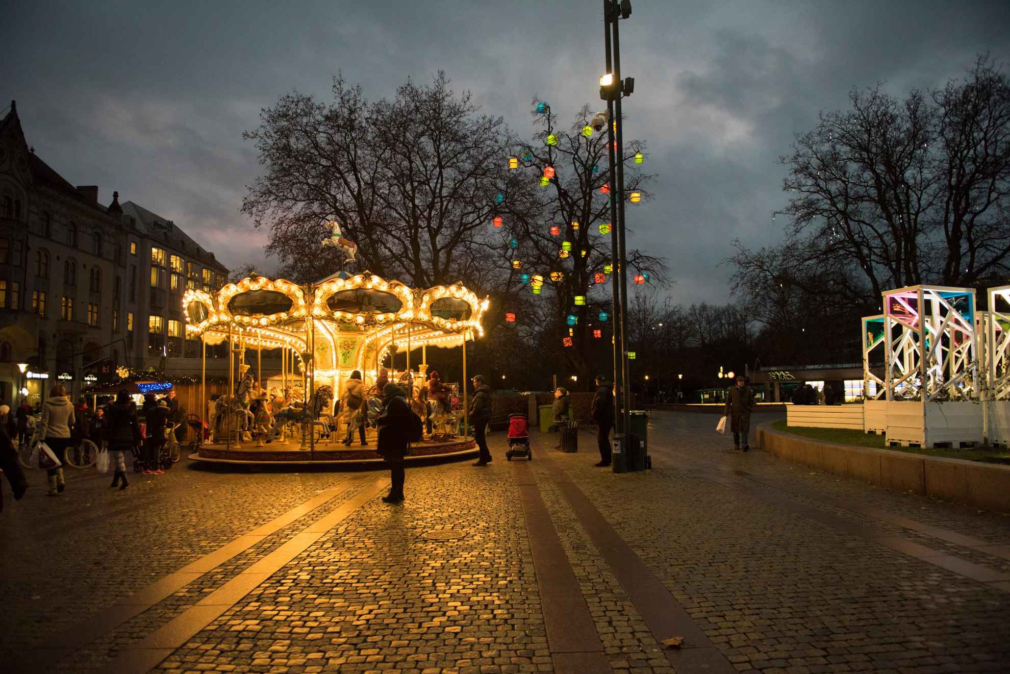 Als het donker is, een openbaar plein met kleurrijke lichten en een carrousel.