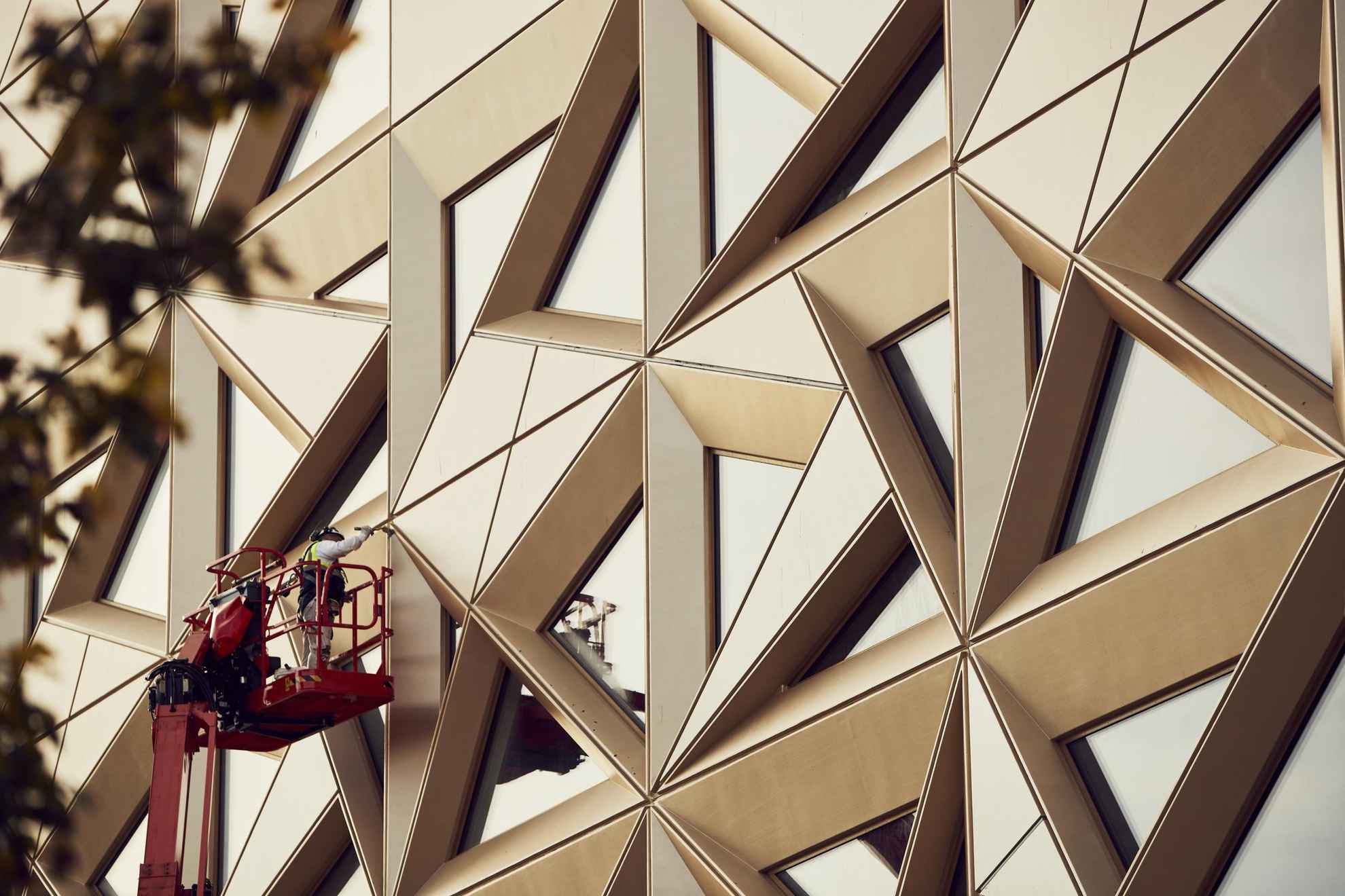 Een persoon in een schilderij van de muur van een gebouw met een glinsterende edelsteenachtige kleur. De gevel en de ramen hebben de vorm van driehoeken.