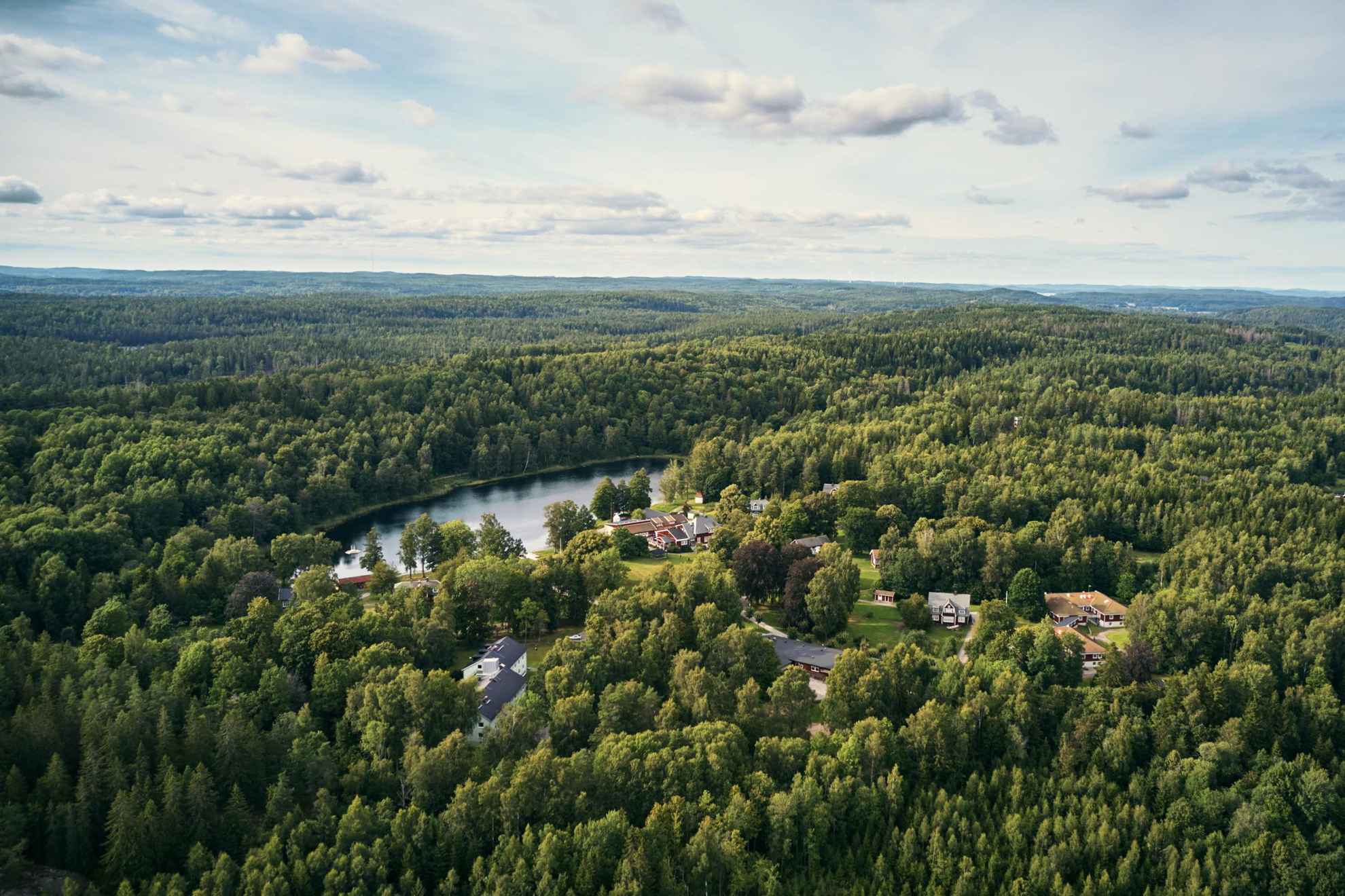 Een luchtfoto van het Kroppefjäll-bos in de zomer. Tussen de bomen zijn een paar huizen zichtbaar.