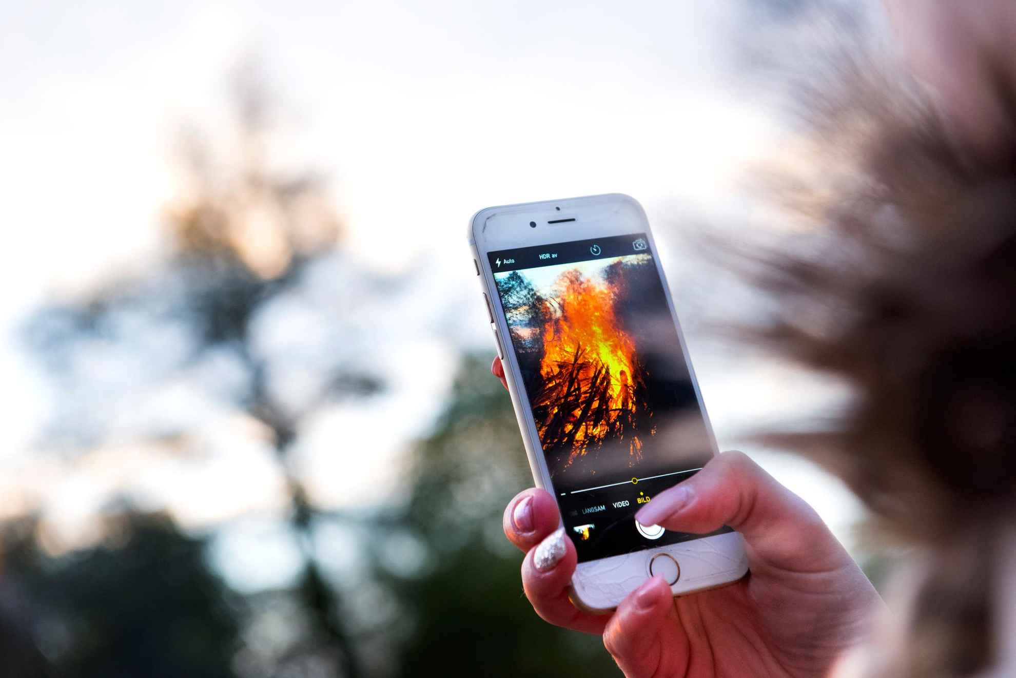 Persoon die zijn telefoon omhoog houdt tijdens het fotograferen van de brand op Walpurgis Eve.