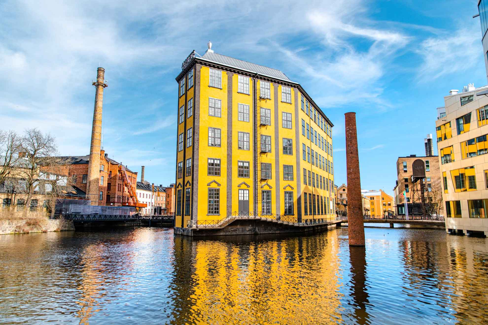 Een industrieel gebouw met een unieke architectuur die doet denken aan een strijkijzer is omgeven door water.