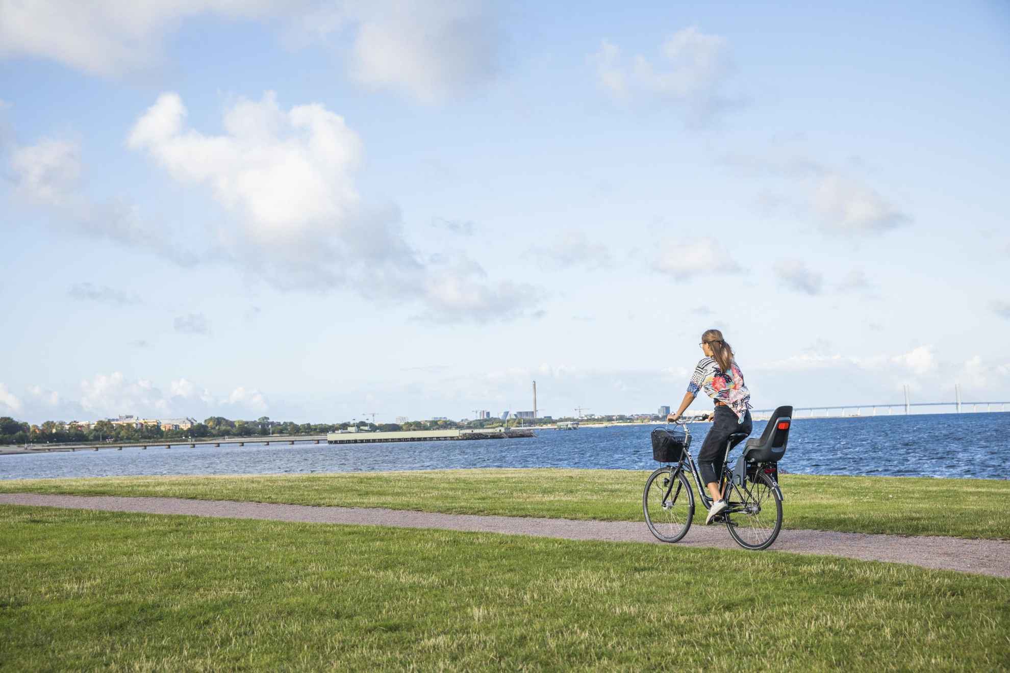 Een vrouw fietst op een pad langs de kust in de westelijke haven van Malmö..