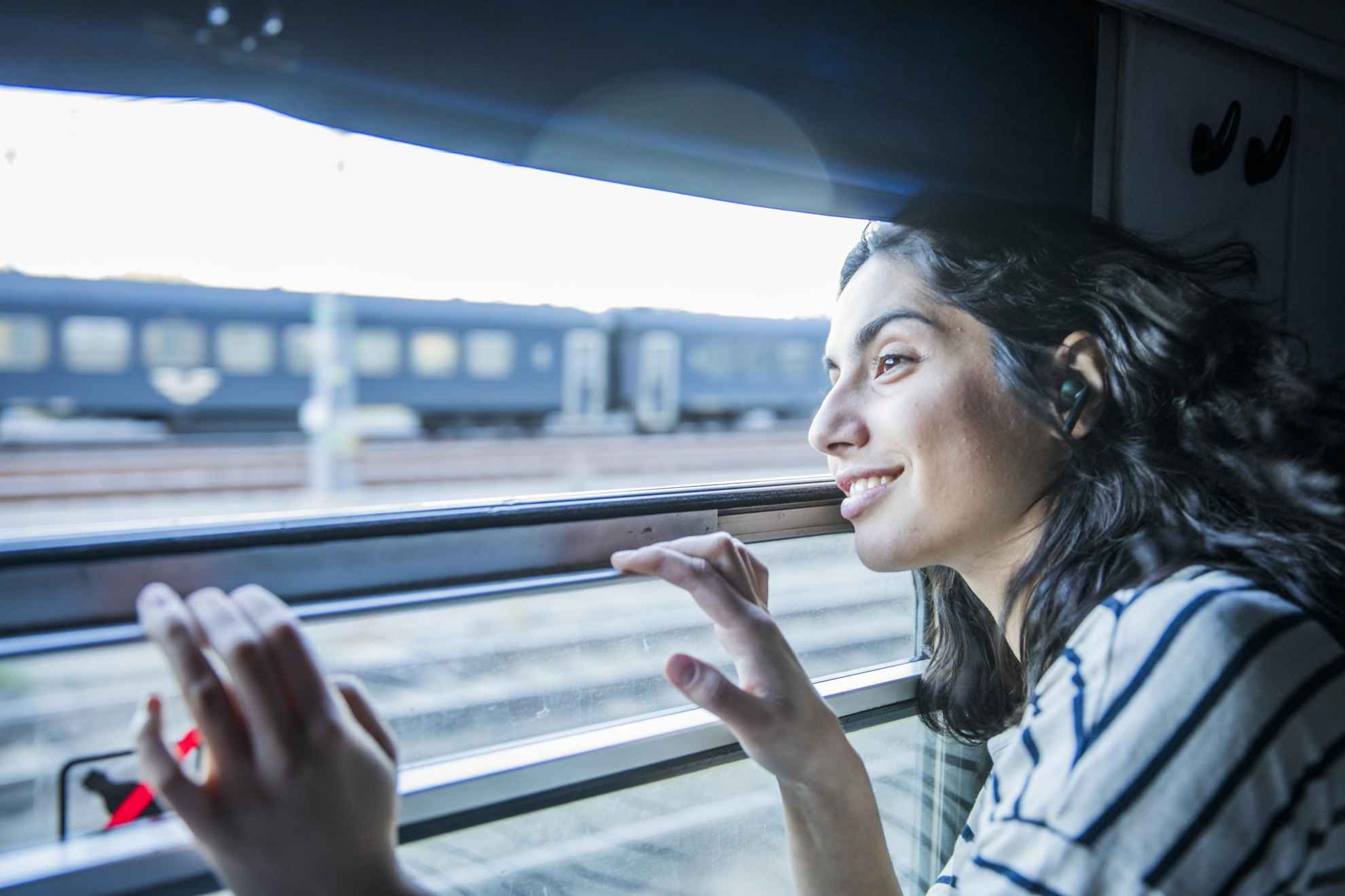 Een vrouw kijkt uit het raam van een trein die een andere trein passeert.