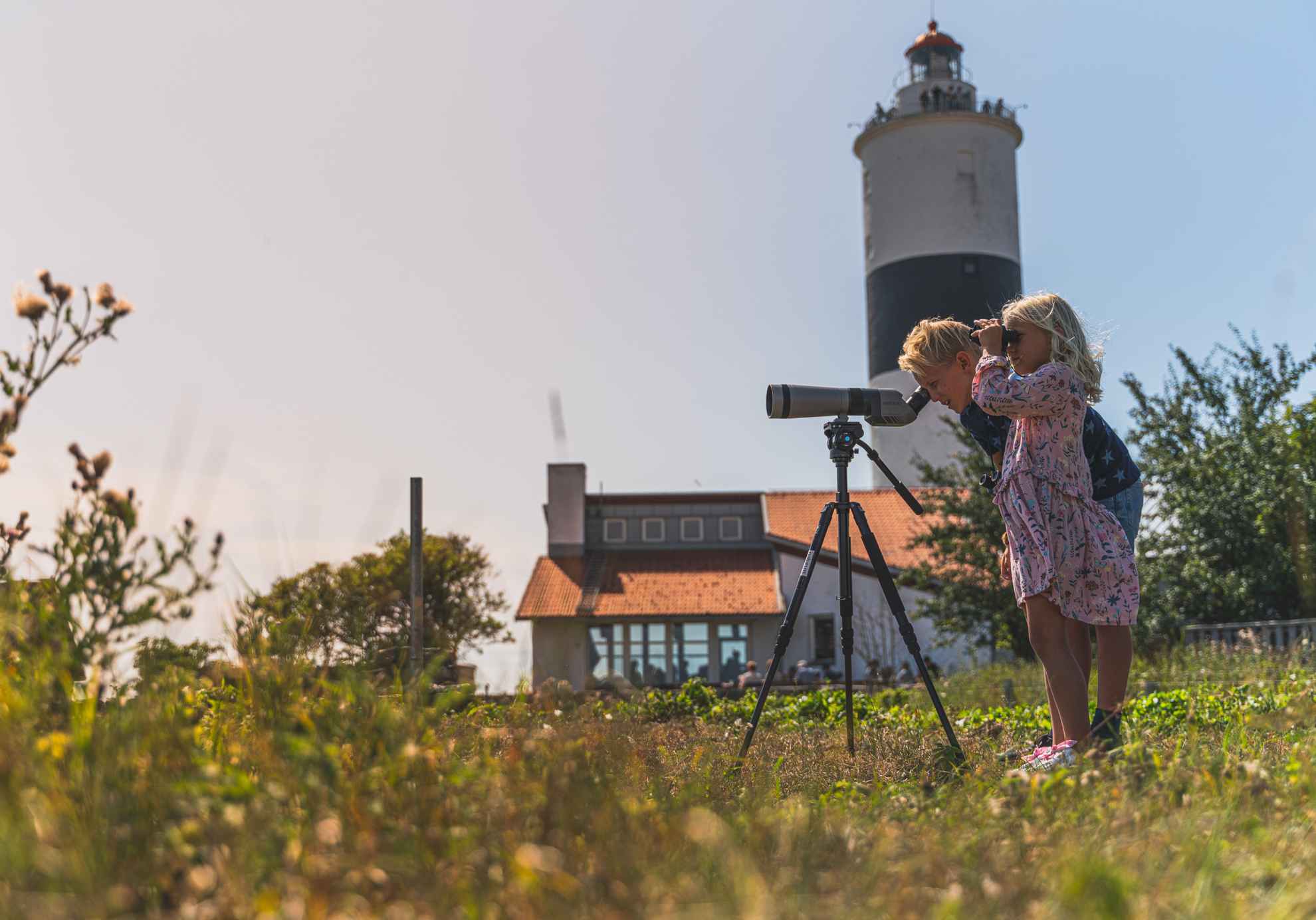 Een meisje en een jongen kijken naar vogels door een telescoop bij de vuurtoren Långe Jan in Öland.