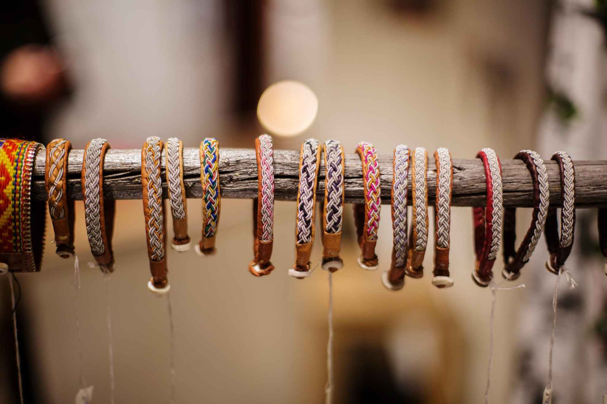 Talrijke armbanden van rendierleer en tindraad, hangend aan een lange stok.