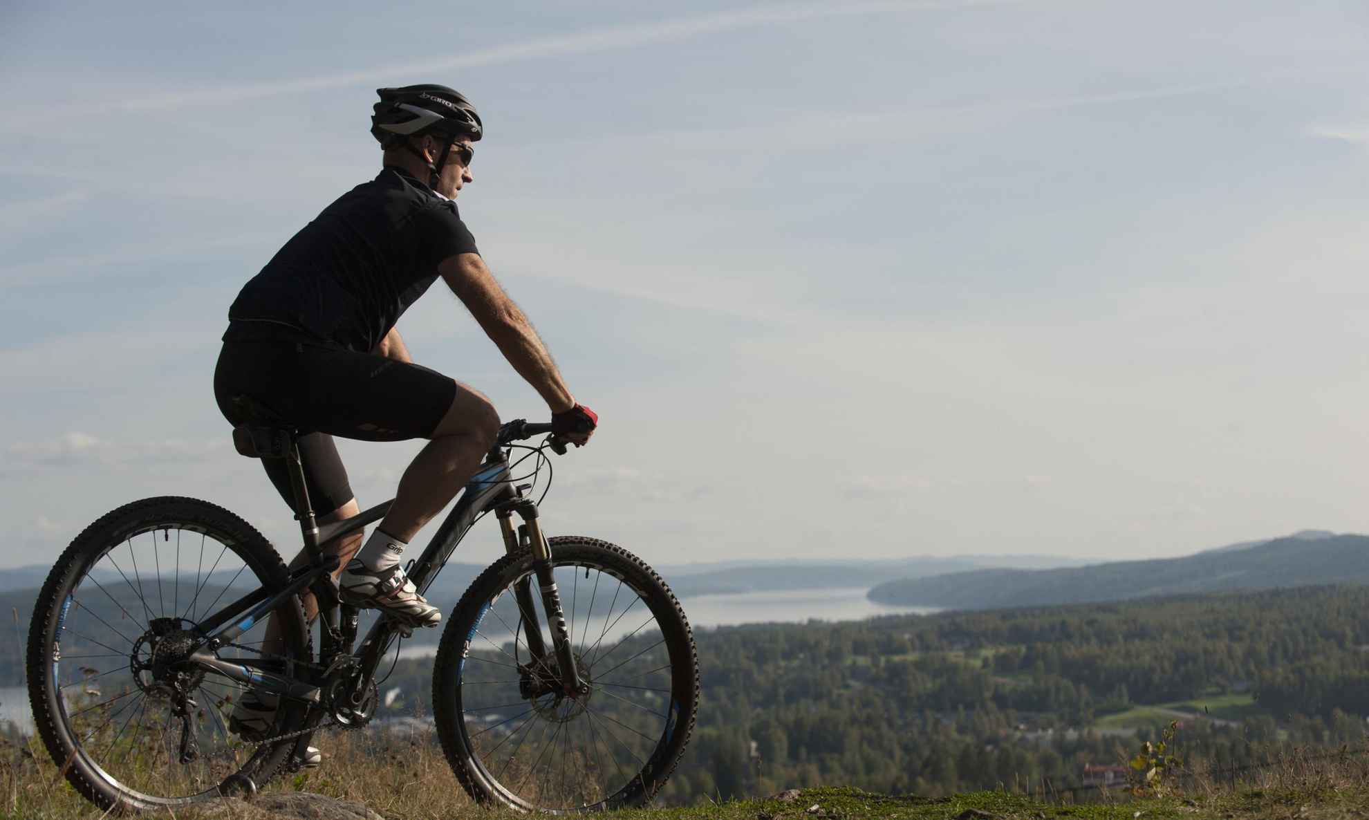 Een man op een mountainbike, uitkijkend over bos en meren in Värmland.