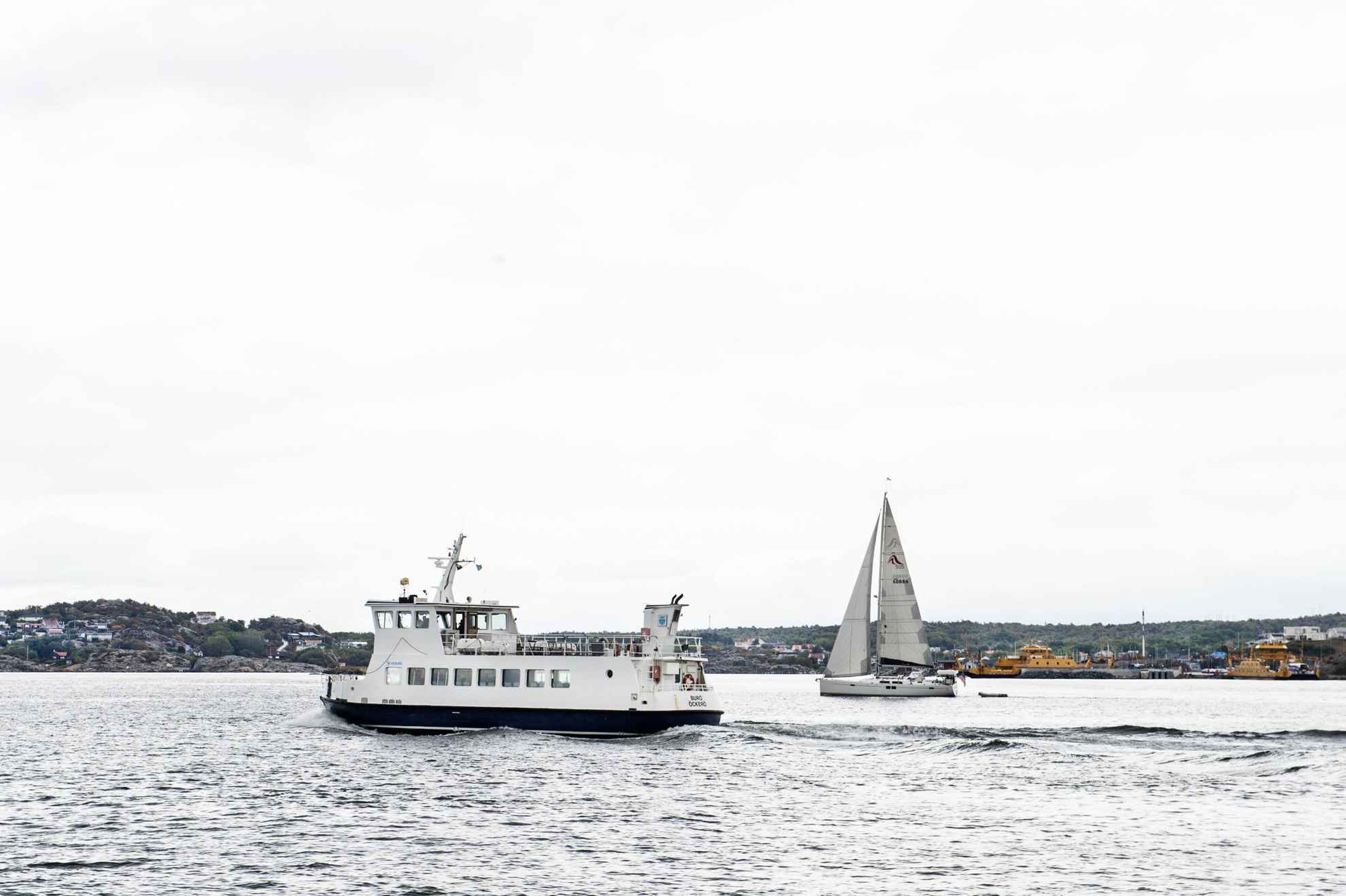 Een kleine veerboot en zeilboot in de zee bij een eiland buiten Göteborg.