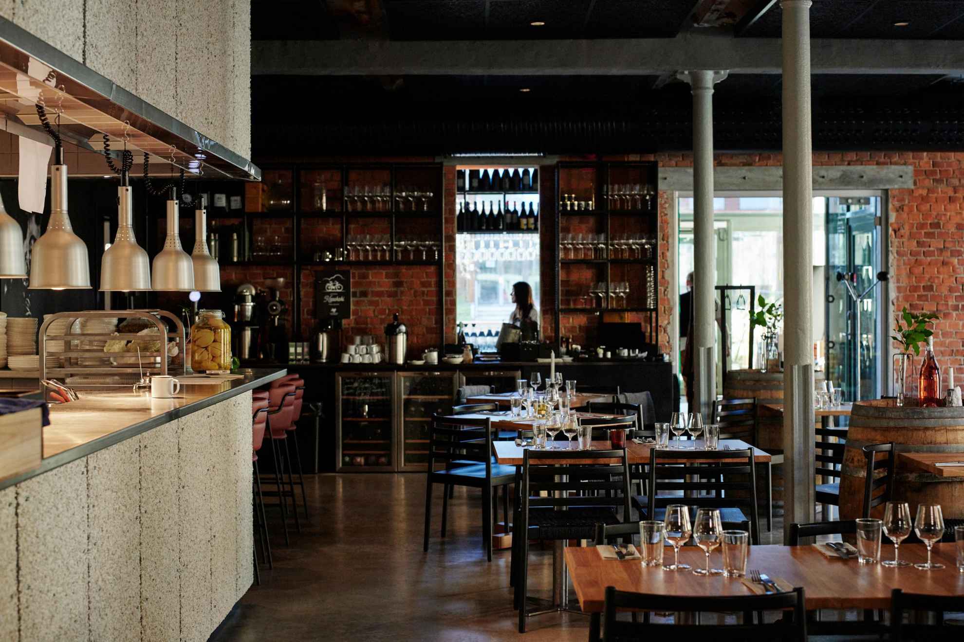 Interieur van een wijnrestaurant met meerdere tafels en links een bar.
