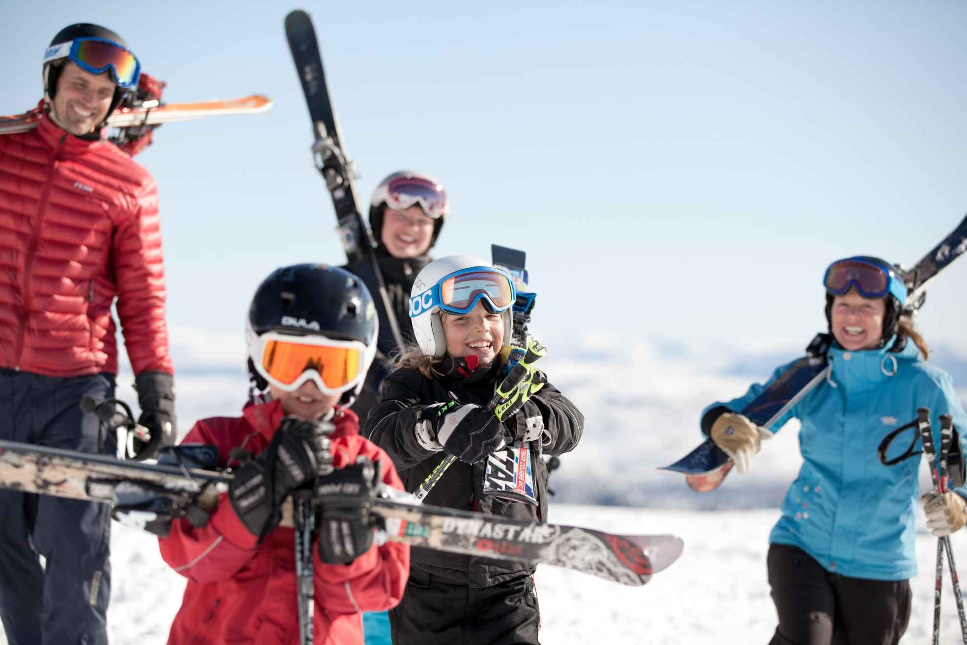 Een gezin met winterkledij, skihelmen en ski's.