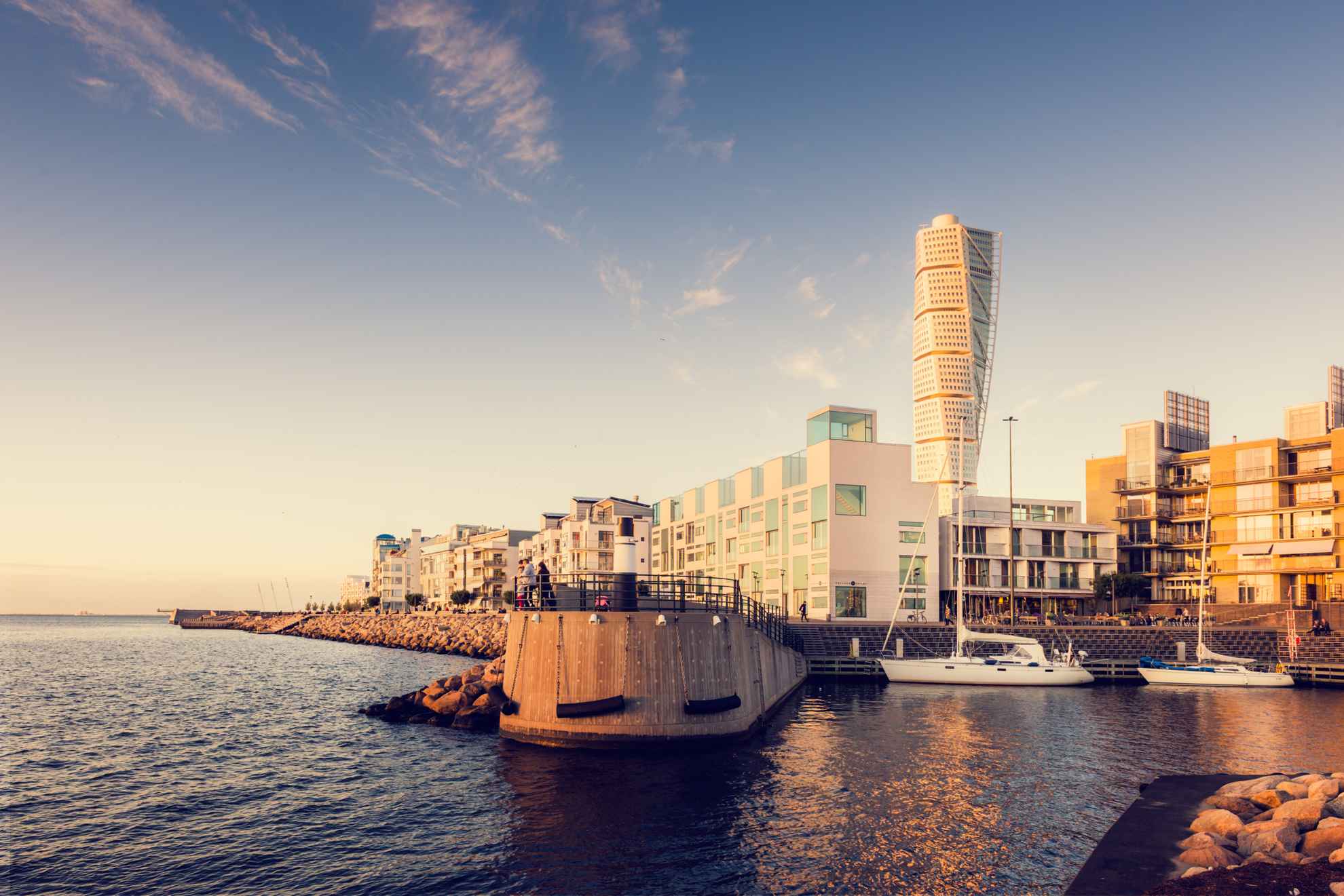 Twee zeilboten liggen aangemeerd in de westelijke haven van Malmö, met de hoogbouw Turning Torso op de achtergrond.