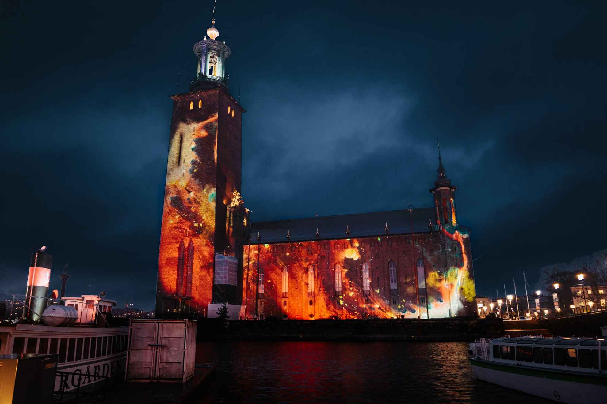 Het aan het water gelegen stadhuis van Stockholm wordt 's nachts verlicht door een lichtscherm.