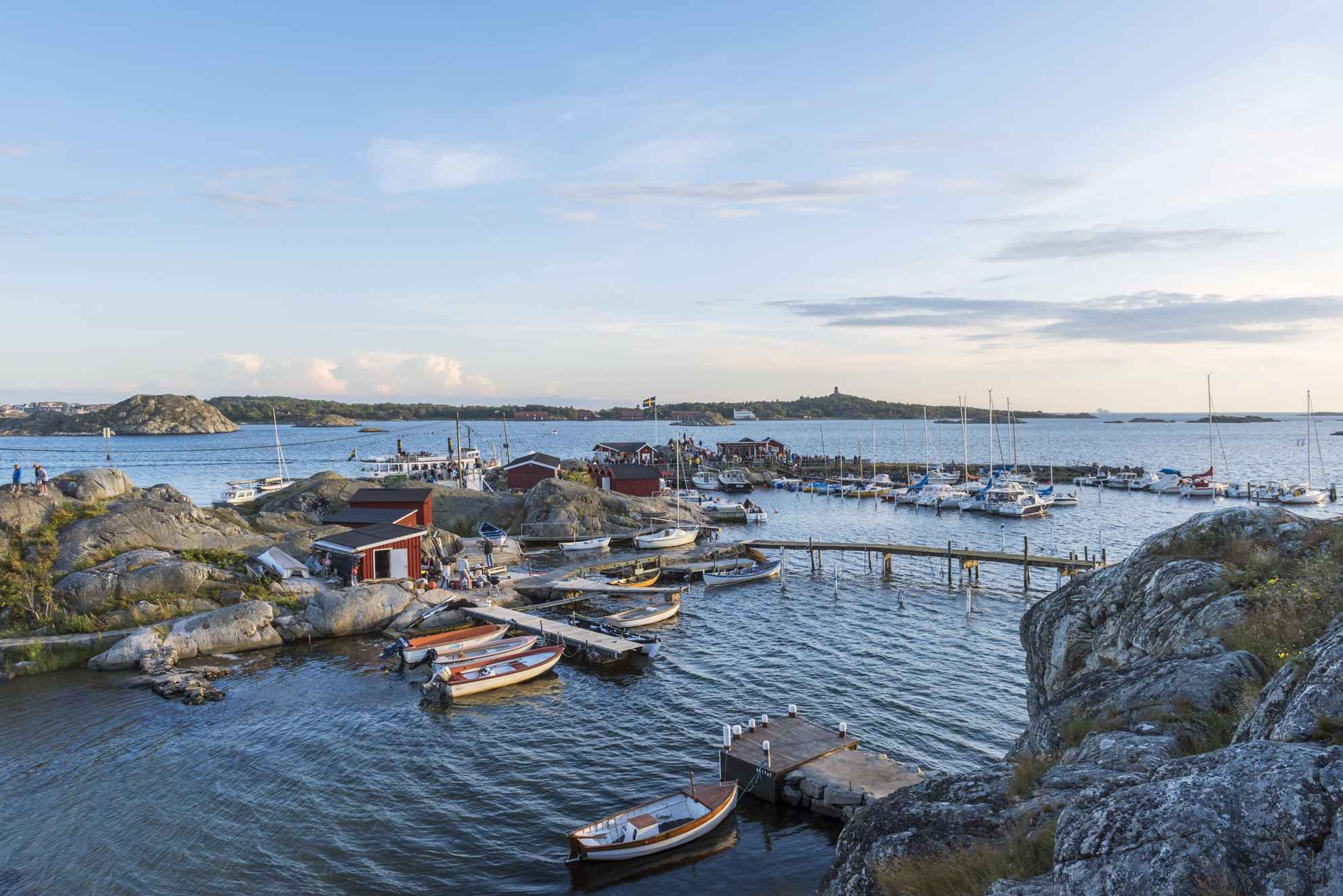 Een kleine jachthaven tussen enkele kliffen in de archipel. Kleine motorboten en zeilboten liggen aan de kade en er zijn verschillende kleine boothuisjes op de kliffen.