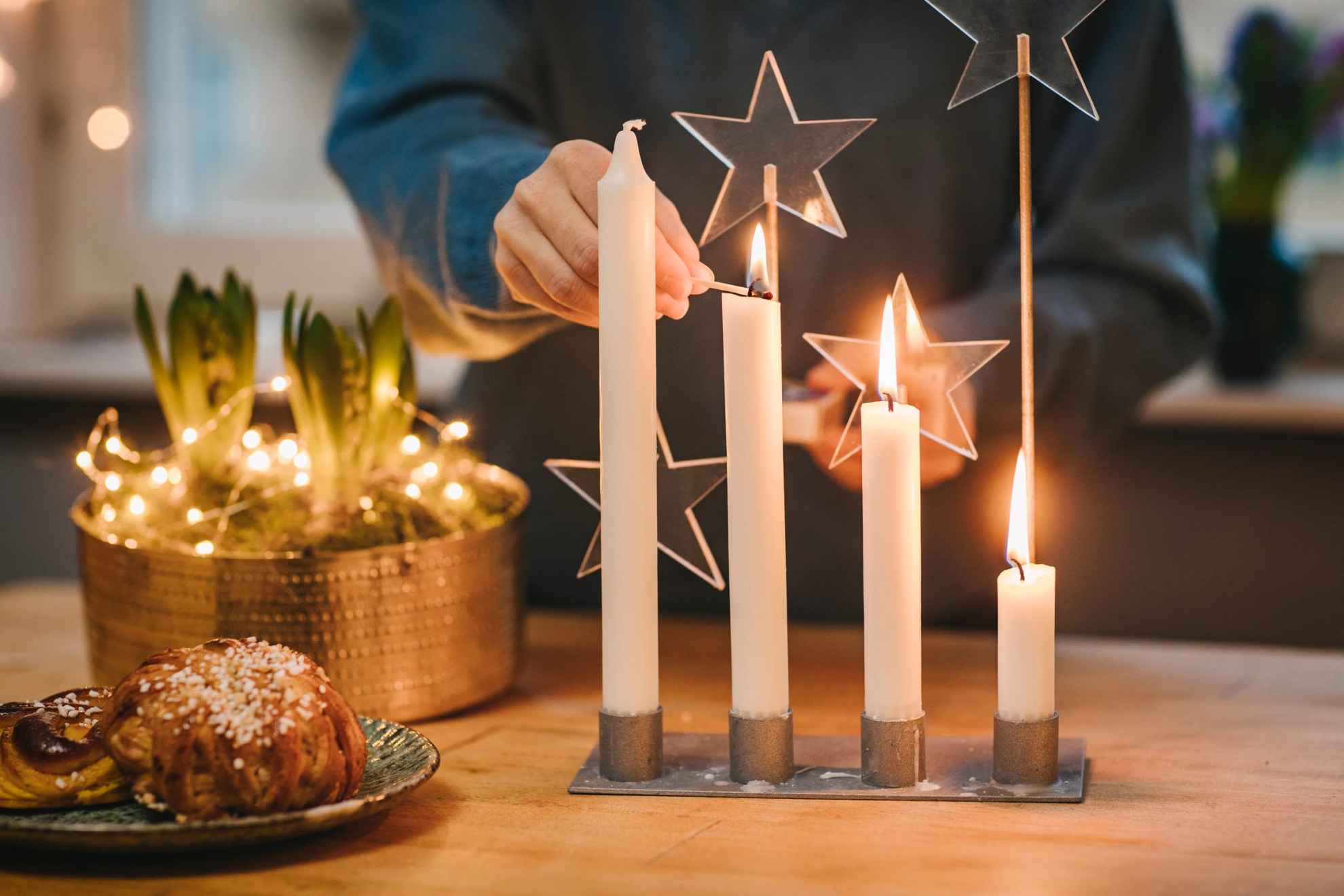 Persoon die kaarsen aansteekt voor advent voorafgaand aan kerst.