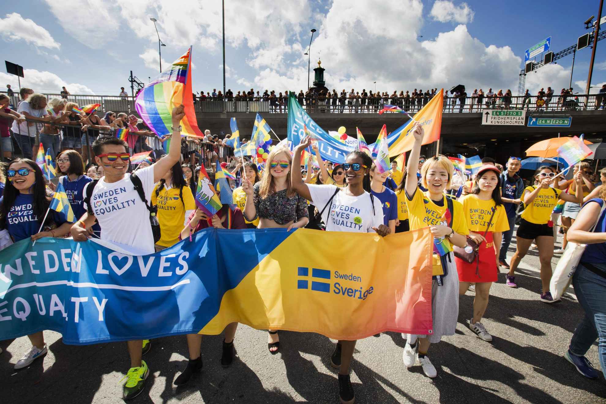 Een menigte mensen zwaait met regenboogvlaggen en houdt borden omhoog met de tekst "Zweden houdt van gelijkheid".