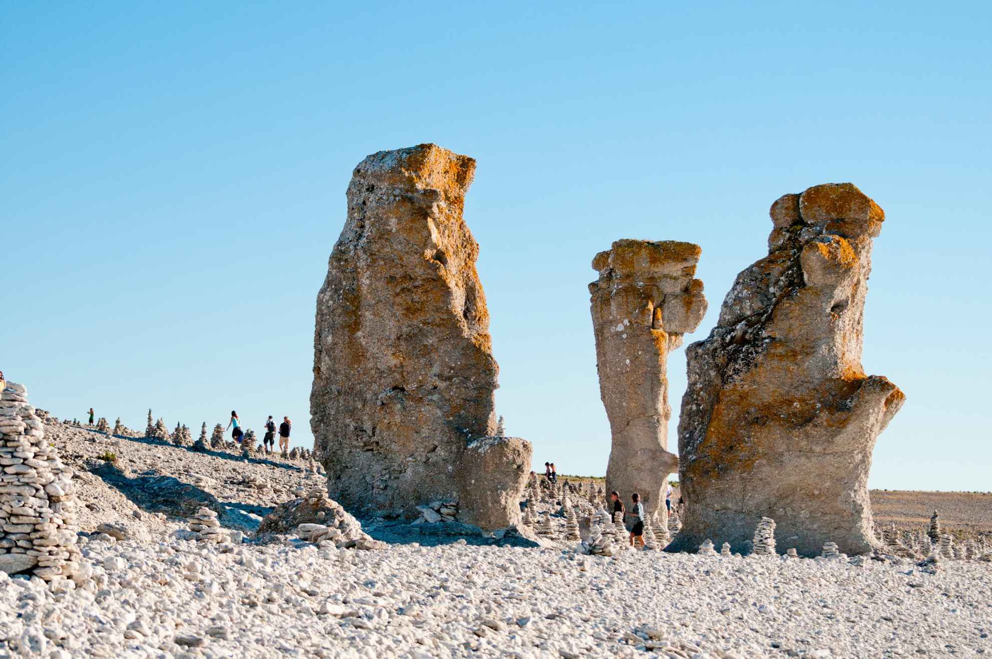 Kalkstenen monolieten op een rotsstrand op Gotland, met een paar mensen op de achtergrond.