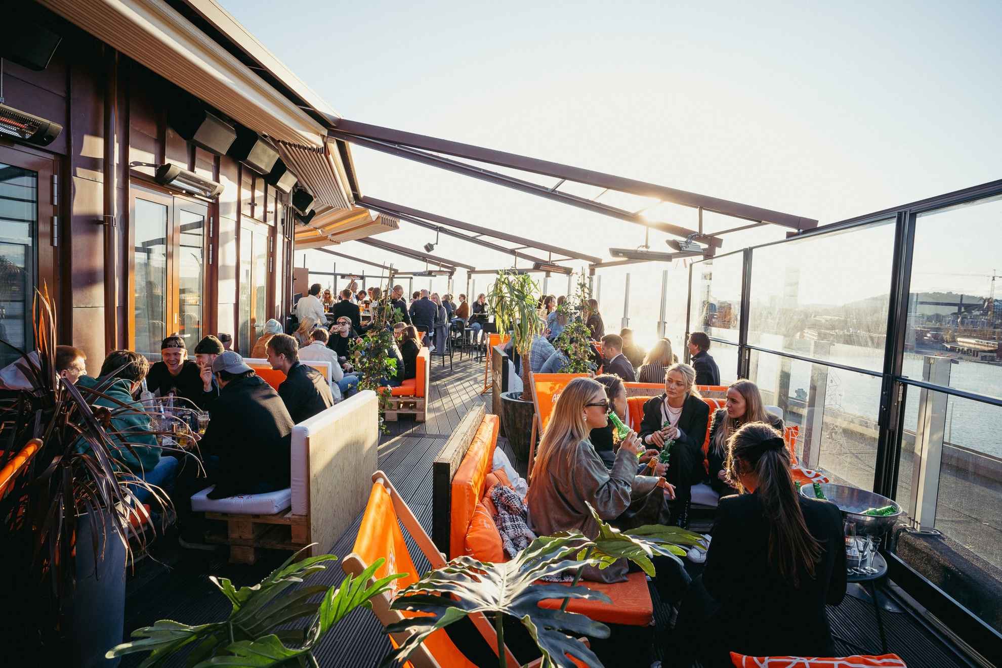 Mensen zitten en genieten van een drankje en het gezelschap van vrienden op het Taket-dak in Göteborg.