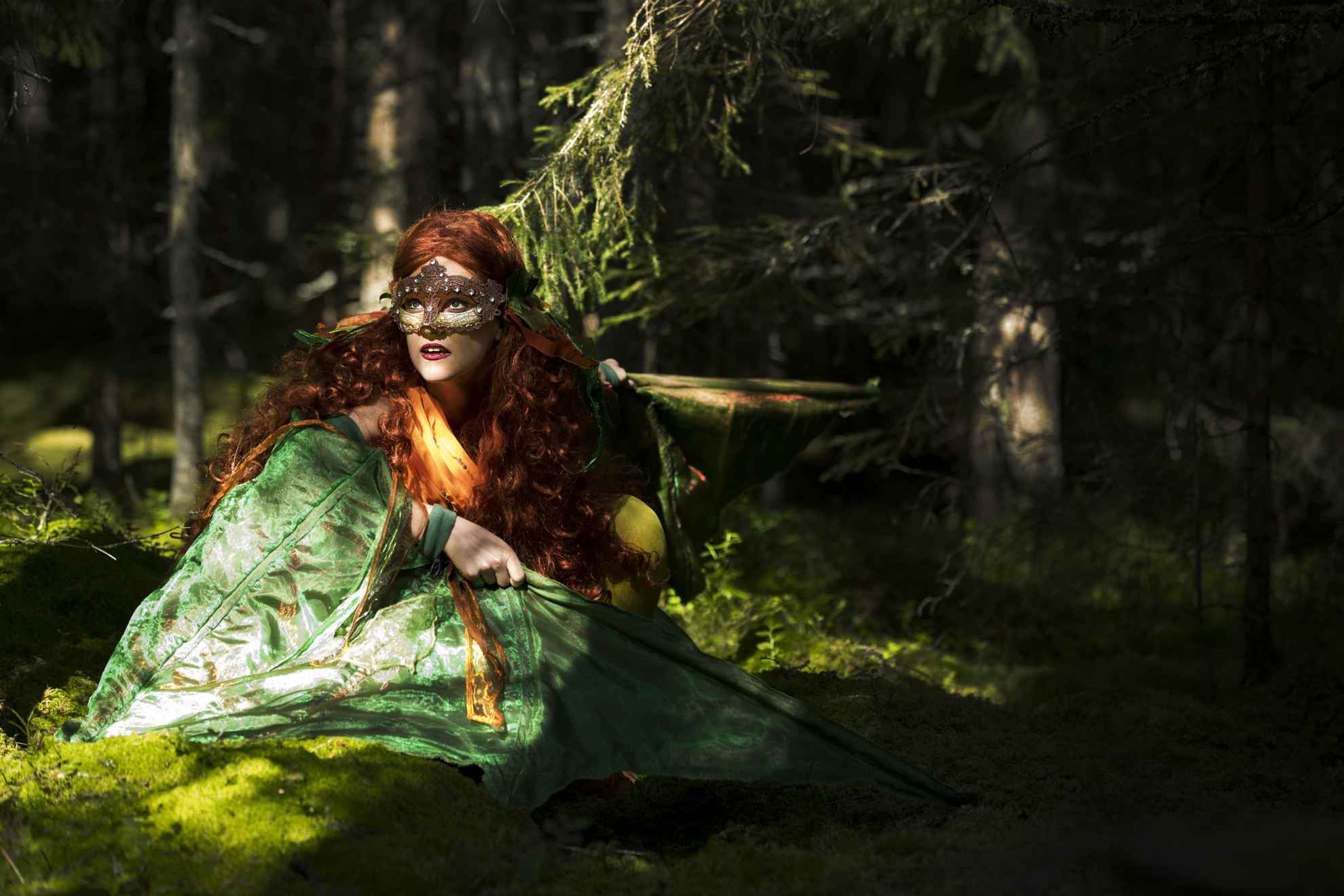 Mythische fee gekleed in het groen met een masker over haar ogen in een weelderig bos.