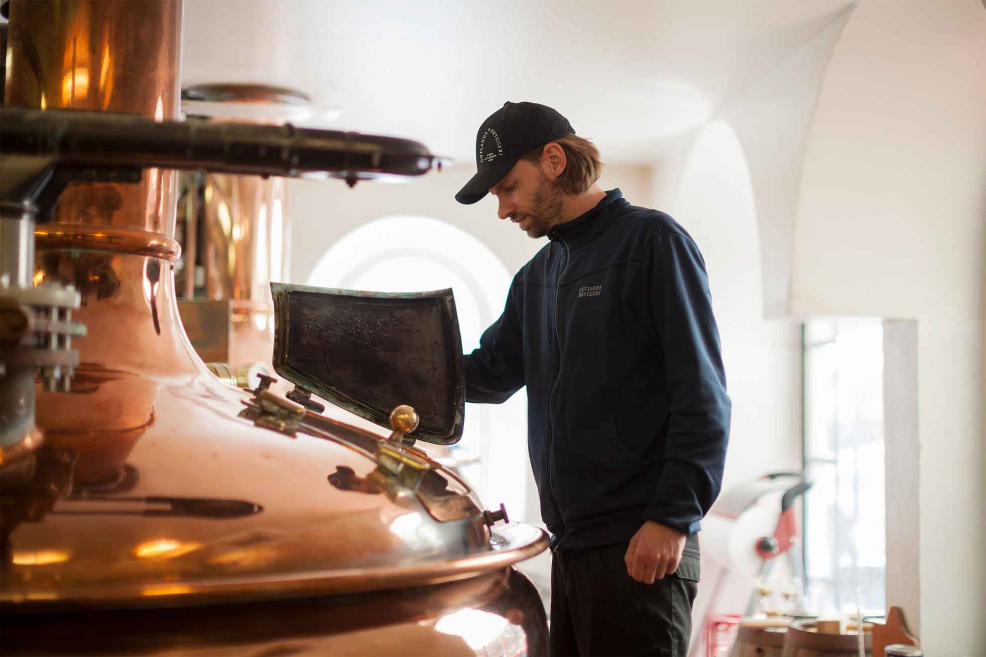 Een medewerker van Gotlands Bryggeri kijkt in een koperen ketel in de brouwerij.