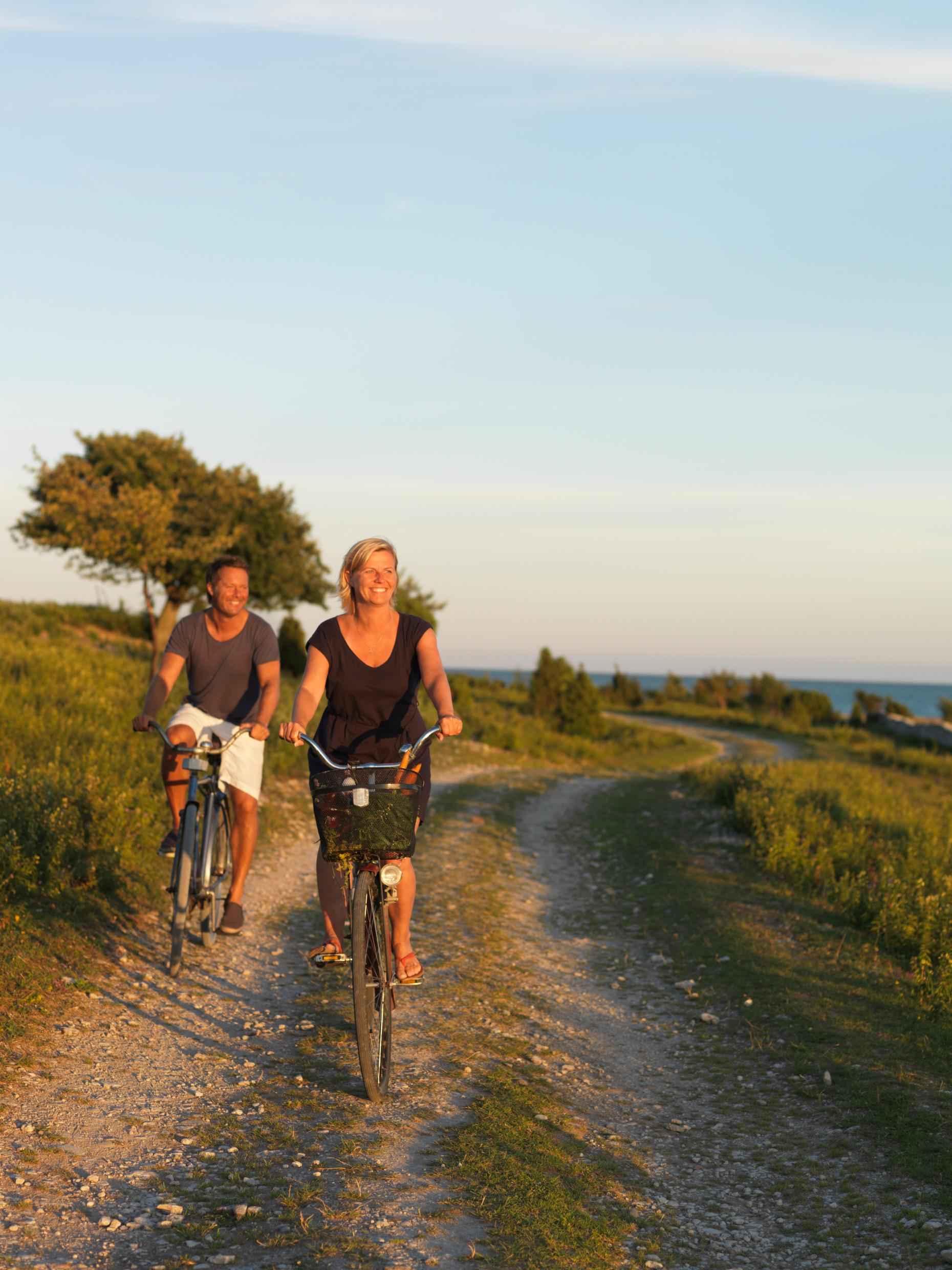 Een vrouw en een man fietsen op een grindpad langs de kust van het eiland Fårö.