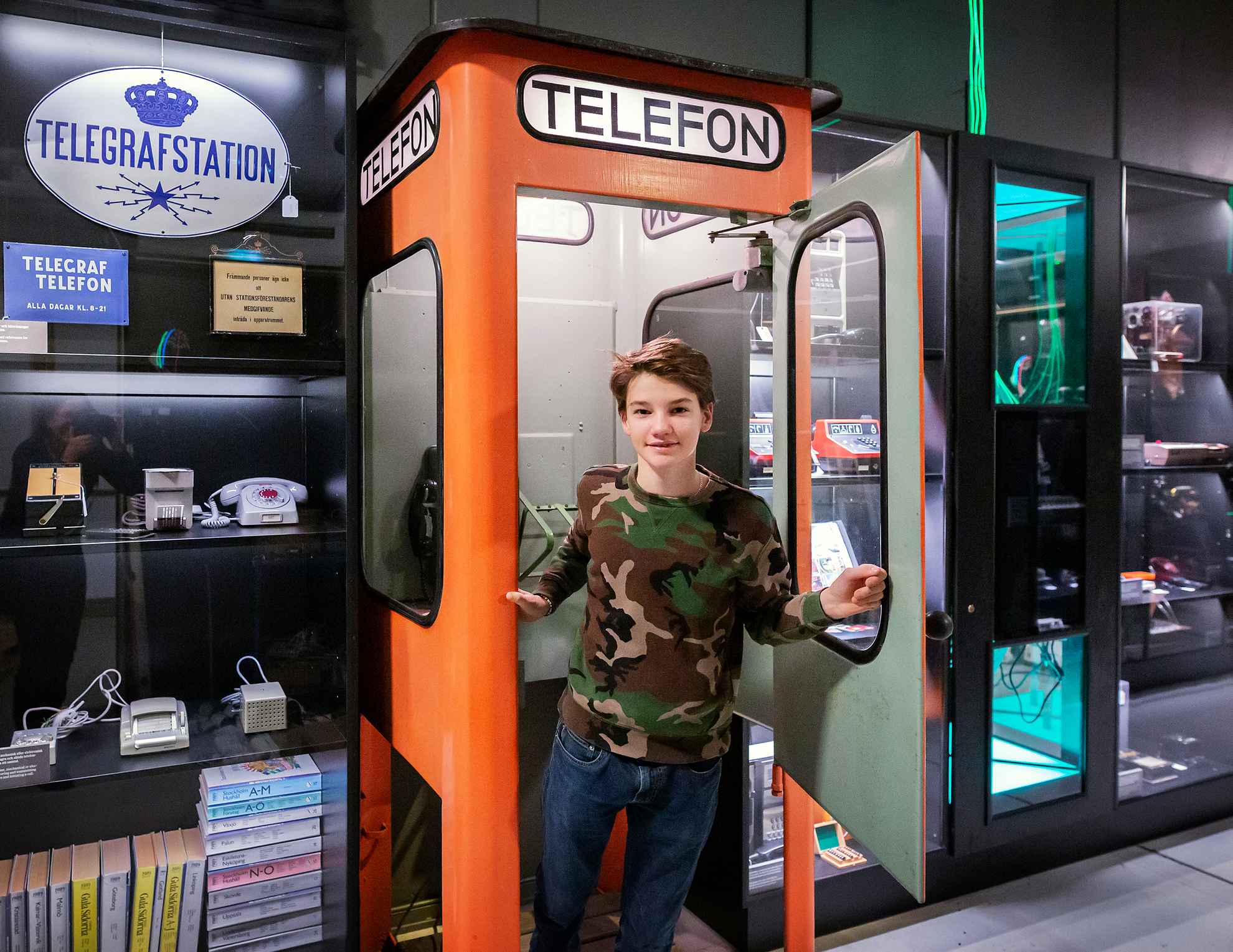 Jonge jongen in een telefooncel in het Nationaal Museum voor Wetenschap en Technologie.