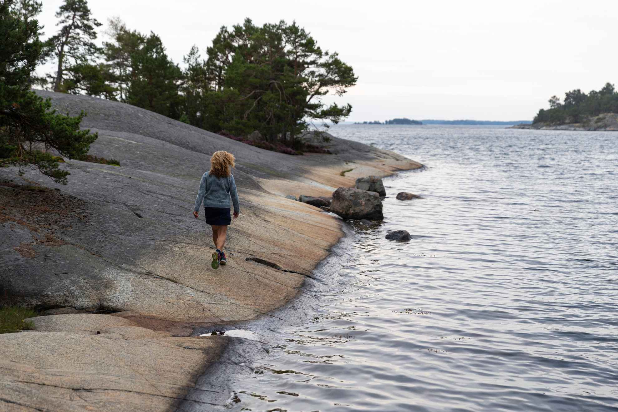 Een vrouw loopt op kliffen langs de waterkant in de archipel van Stockholm.