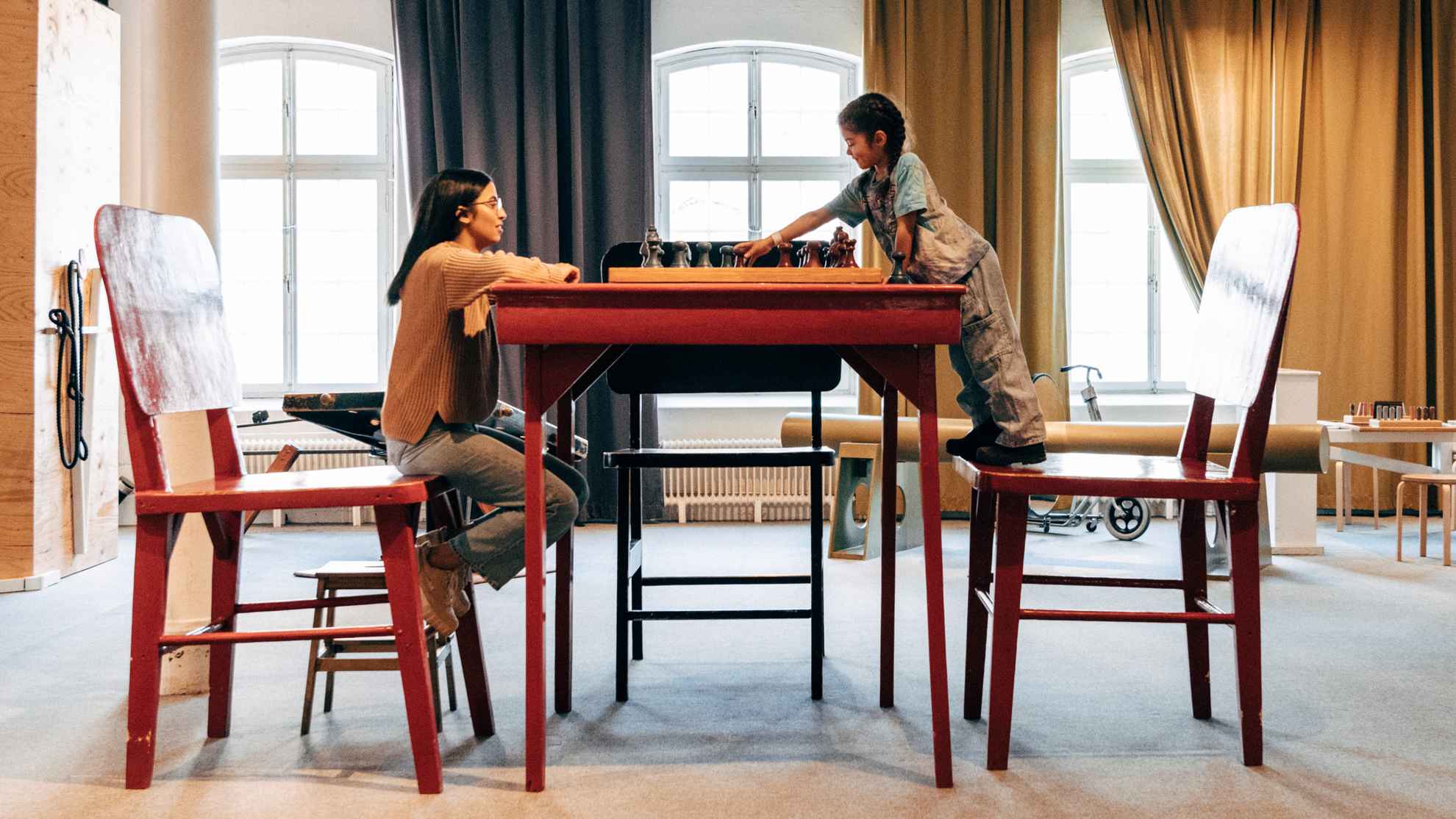Vrouw en kind schaken aan een enorme tafel bij Tom Tits.