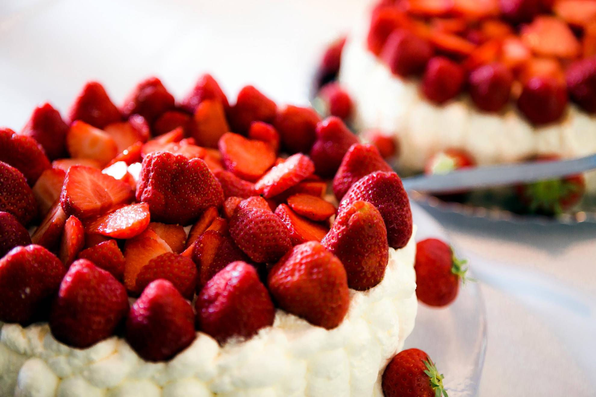 Twee taarten met slagroom en aardbeien.