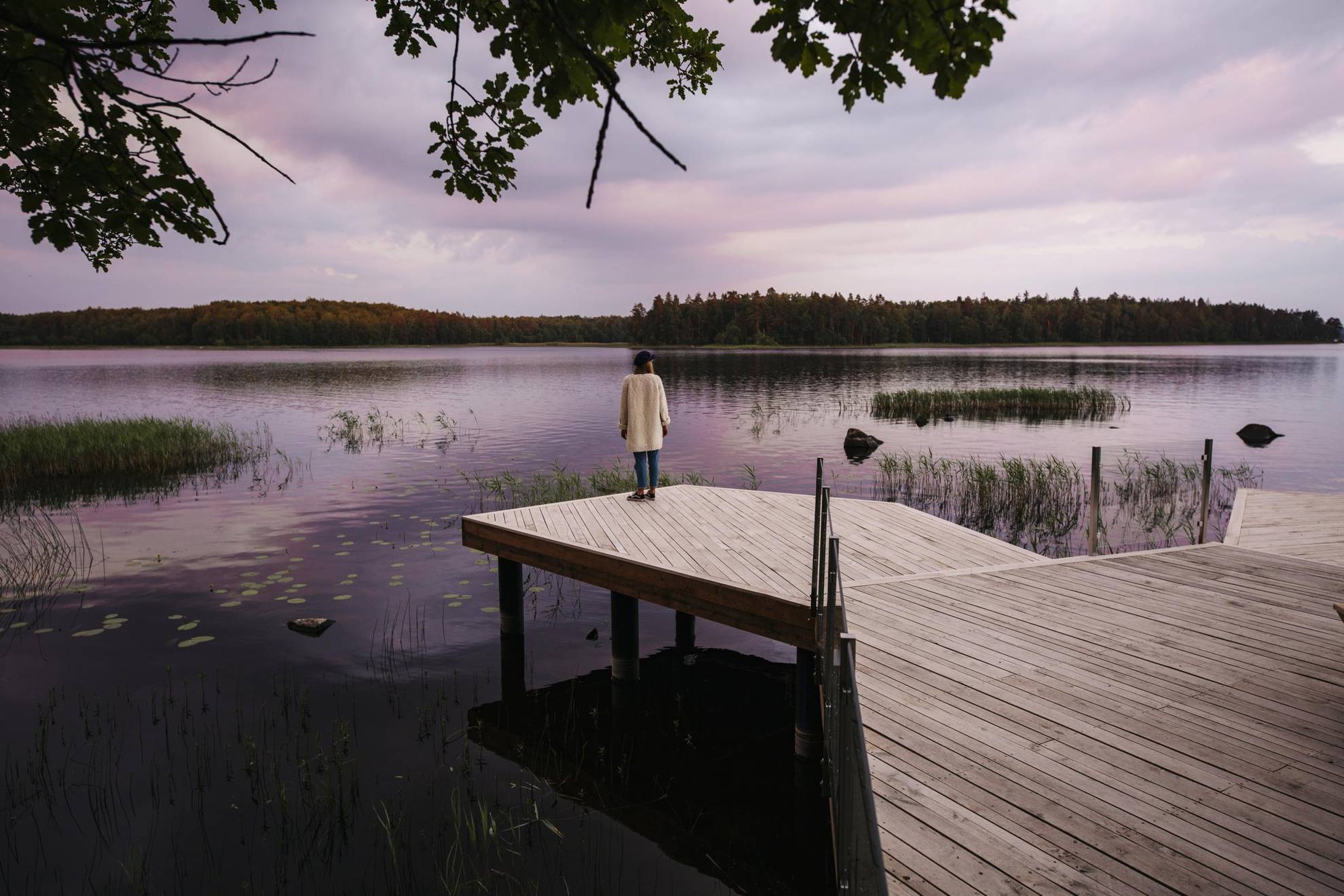 Een vrouw staat aan de rand van een steiger terwijl ze geniet van het uitzicht op een meer.