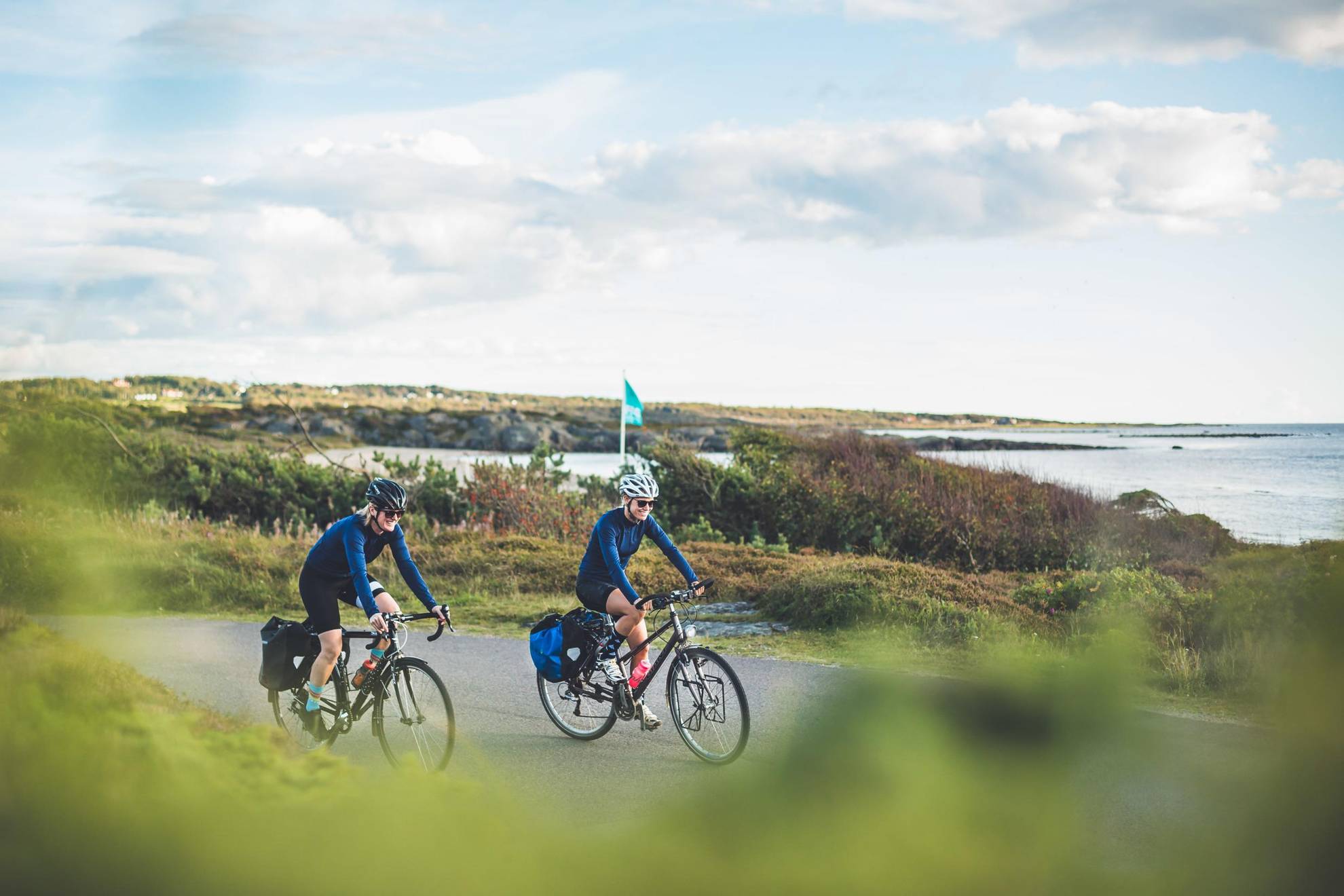 Een stel fietst op een weg langs de zee in Halland.