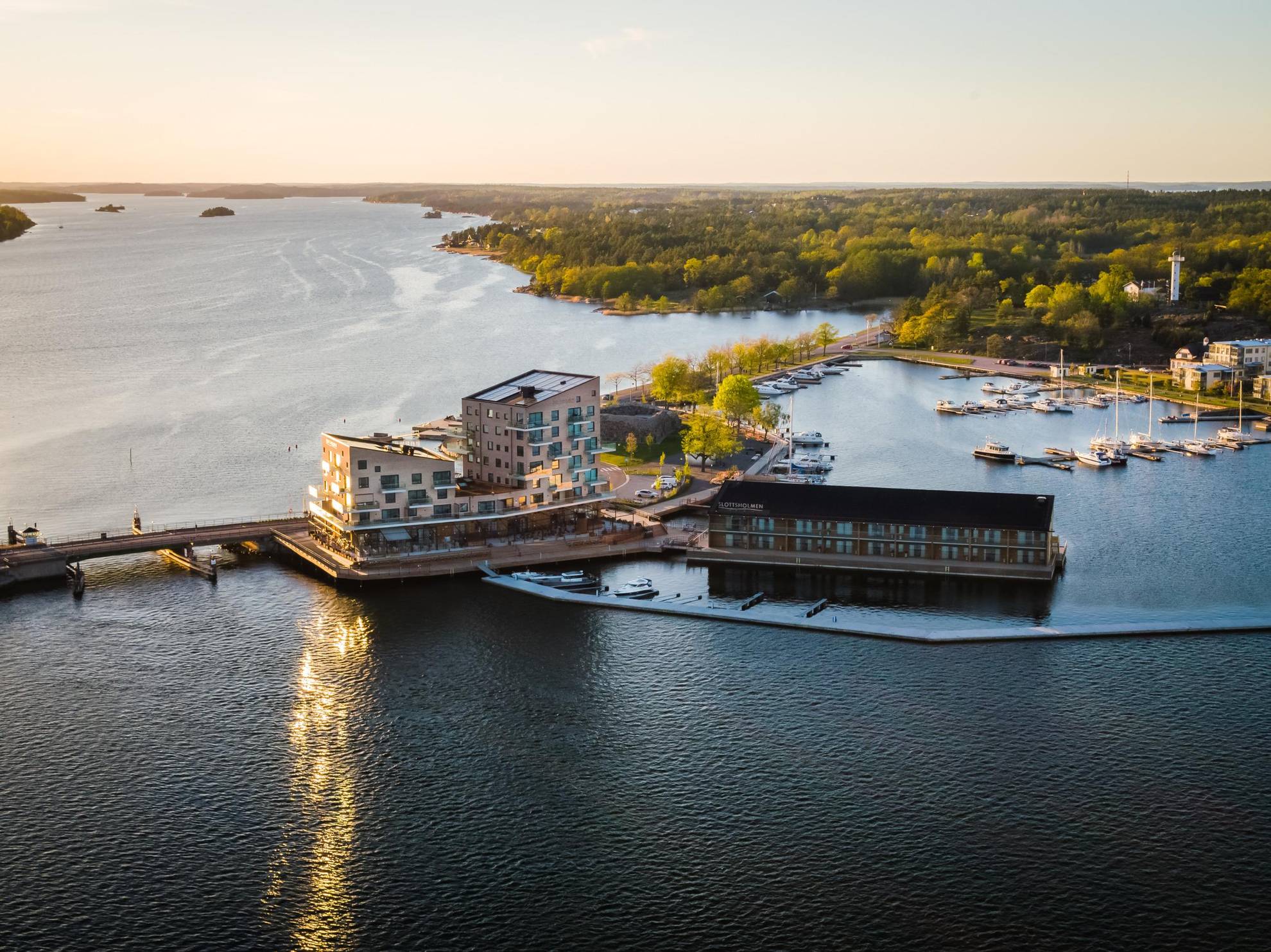 Luchtfoto van het hotel Slottsholmen en zijn grote terras, omgeven door water en gelegen aan een kleine haven.