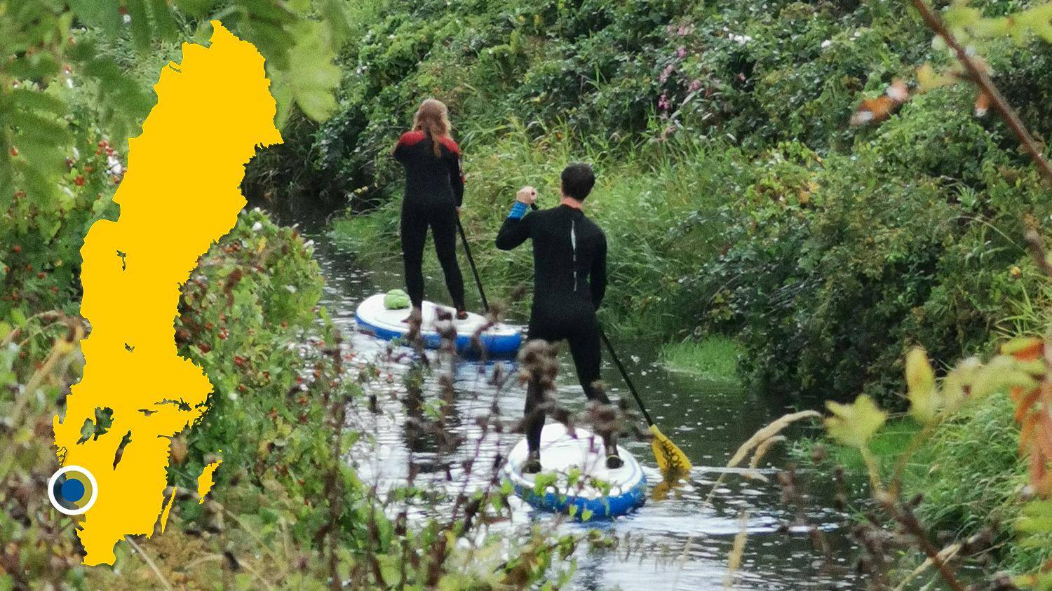 Twee mensen peddelen op stand-up paddleboards in een rivier. Er is een gele kaart van Zweden met een markering die Himleån lokaliseert.