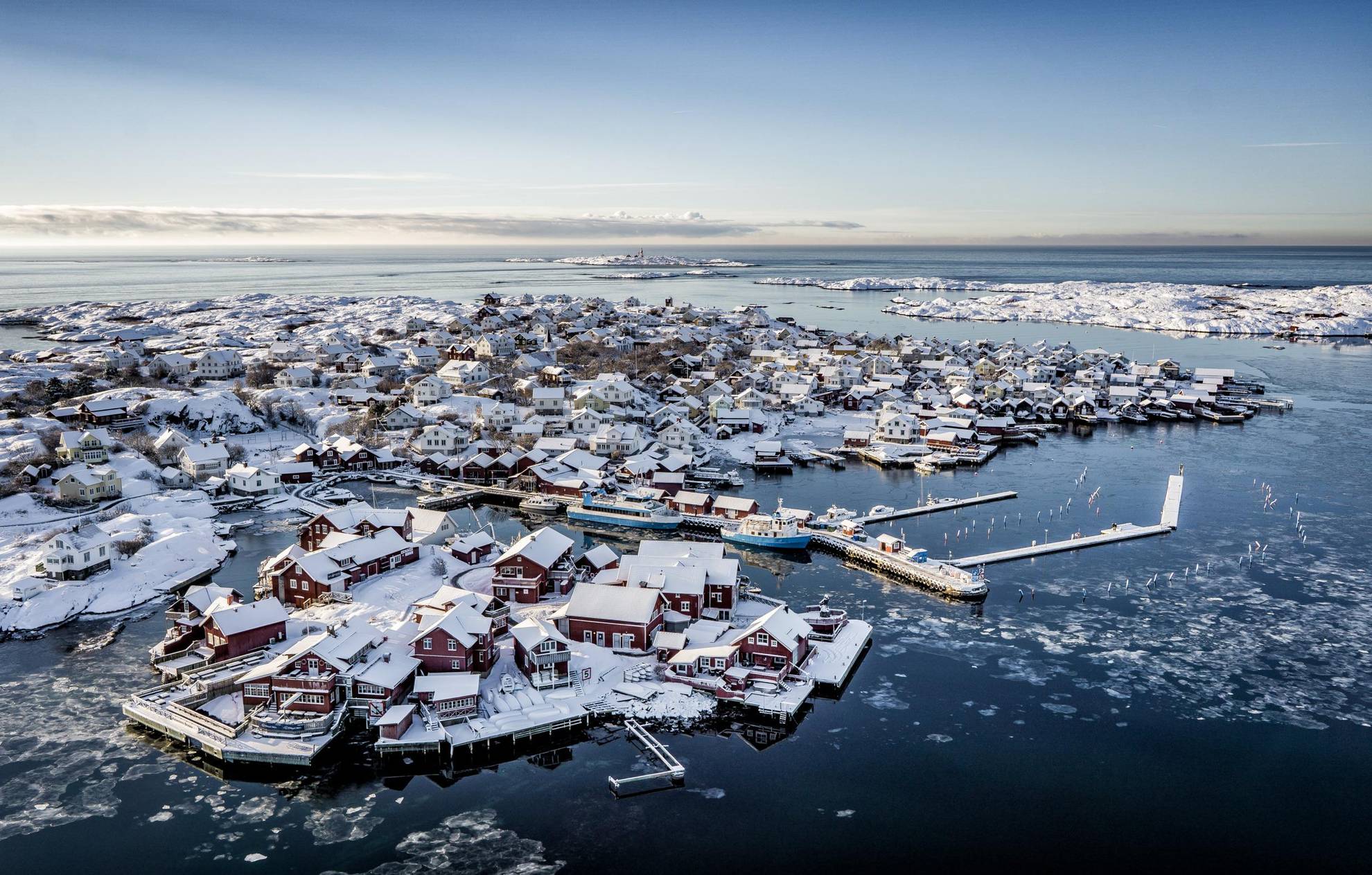 Een luchtfoto van een besneeuwd eiland met huizen en een haven.