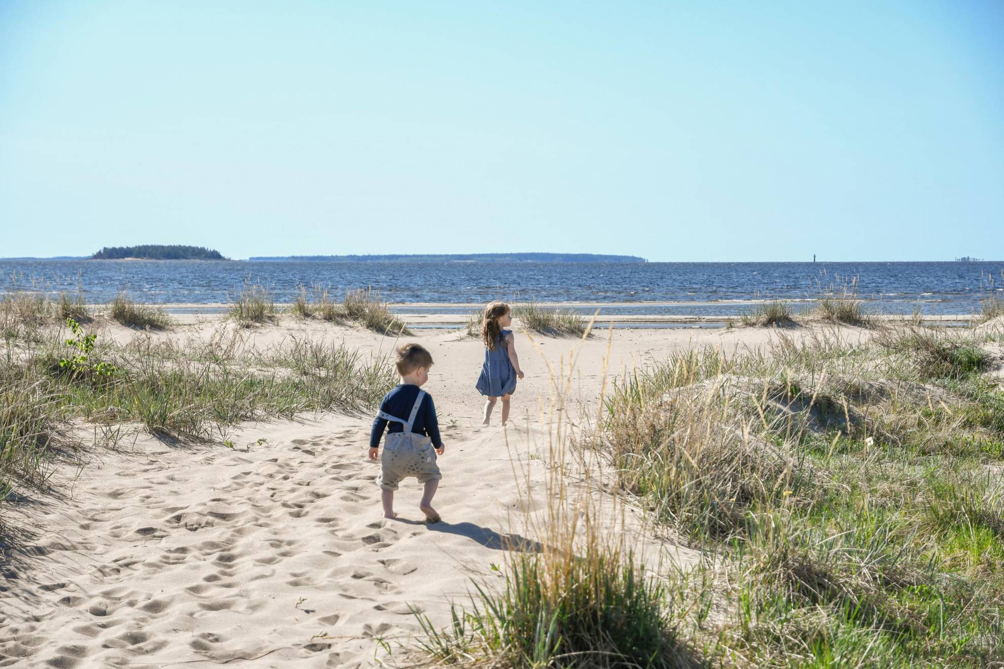Twee kinderen lopen in de zomer op een strand.
