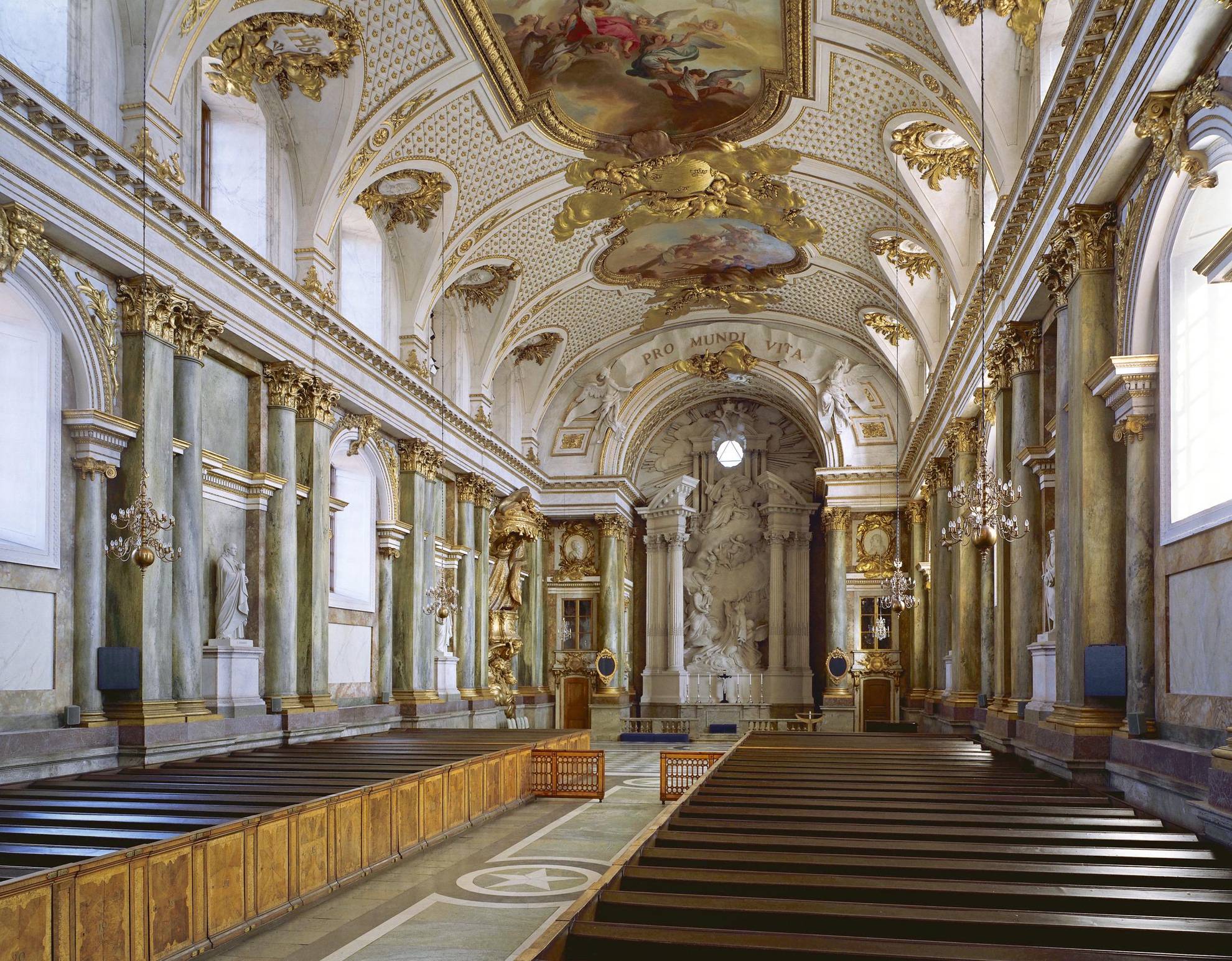 Het interieur van de Koninklijke Kapel heeft witte muren en gouden details. Sculpturen langs de muren en aan de voorkant, en een groot schilderij in het plafond.