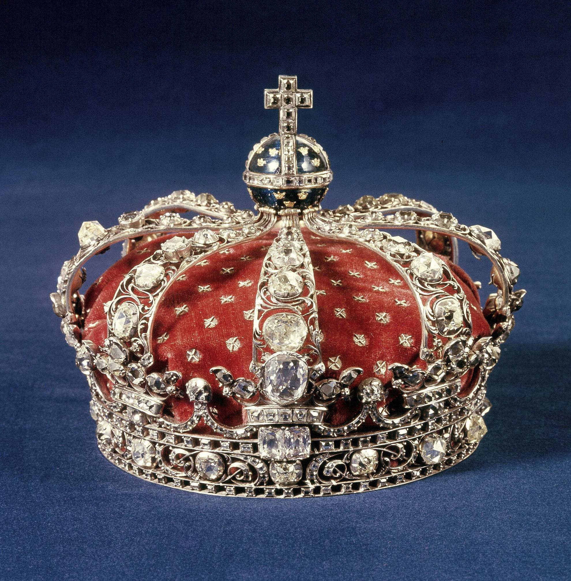 Een met juwelen bezette kroon met diamanten en goud, rustend op blauw fluweel.